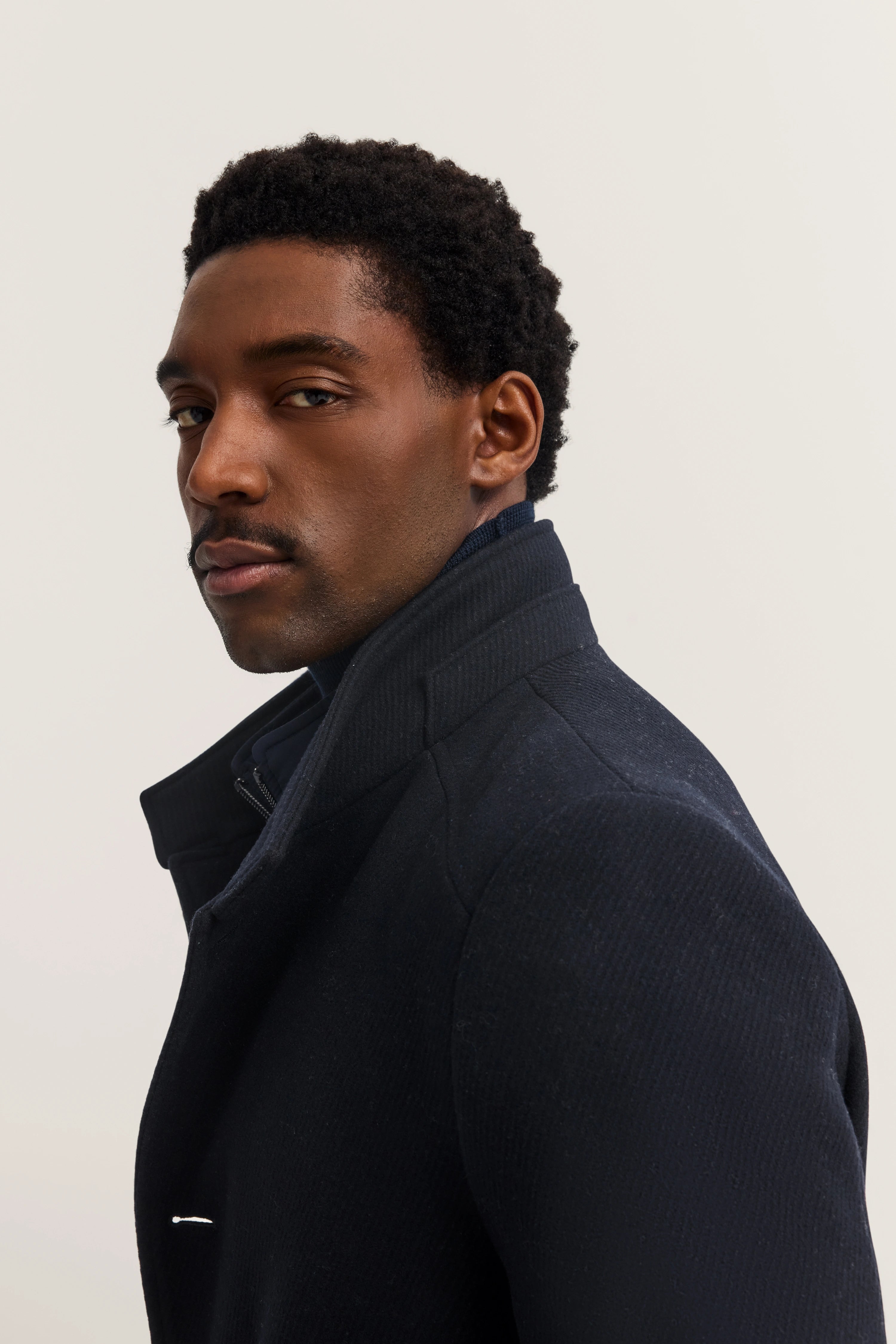 Bust image in navy bugatti coat, exuding elegant look and timeless sophistication.