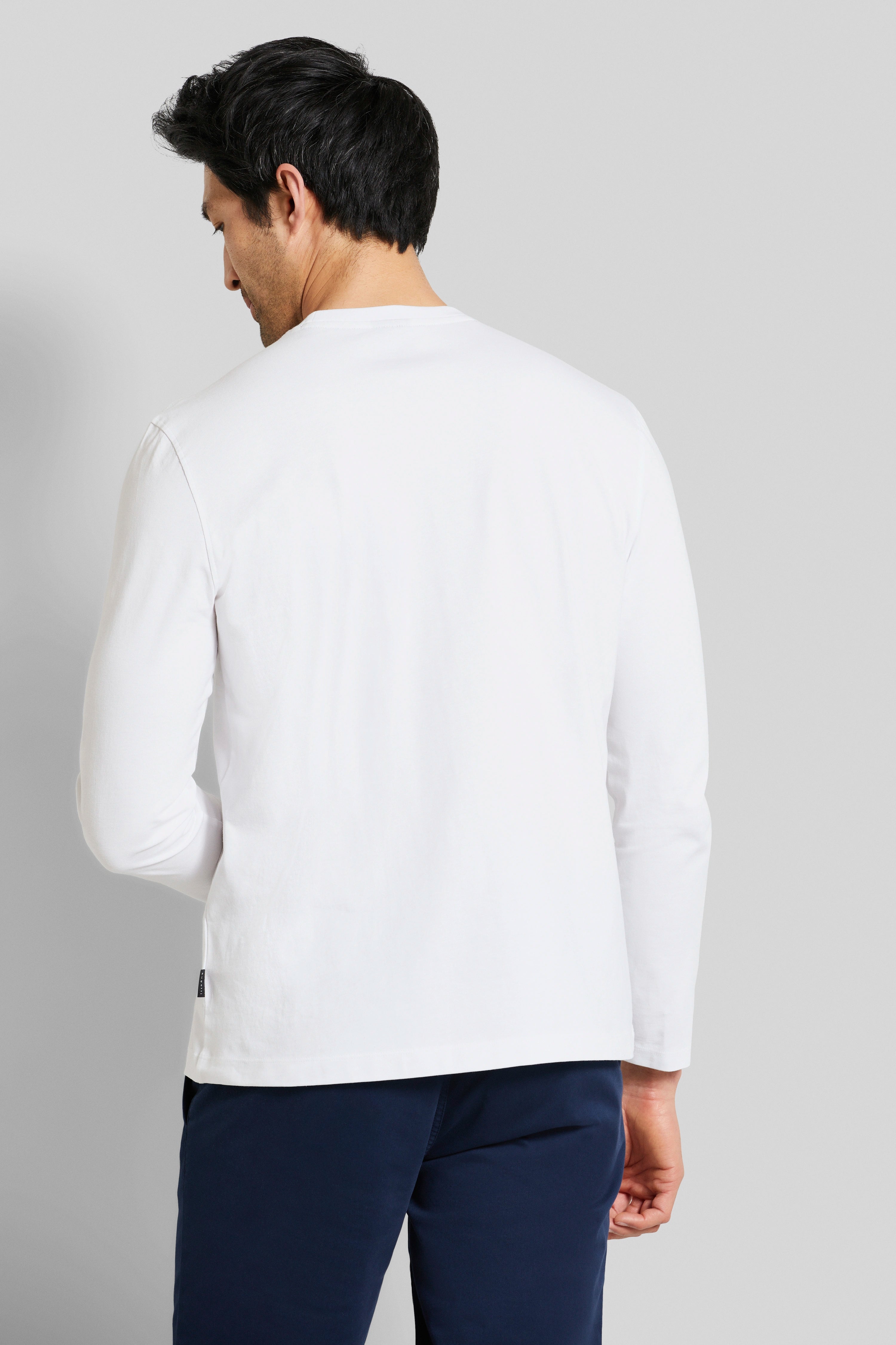 White long-sleeve shirt, back view, with dark blue pants, casual model image from behind.