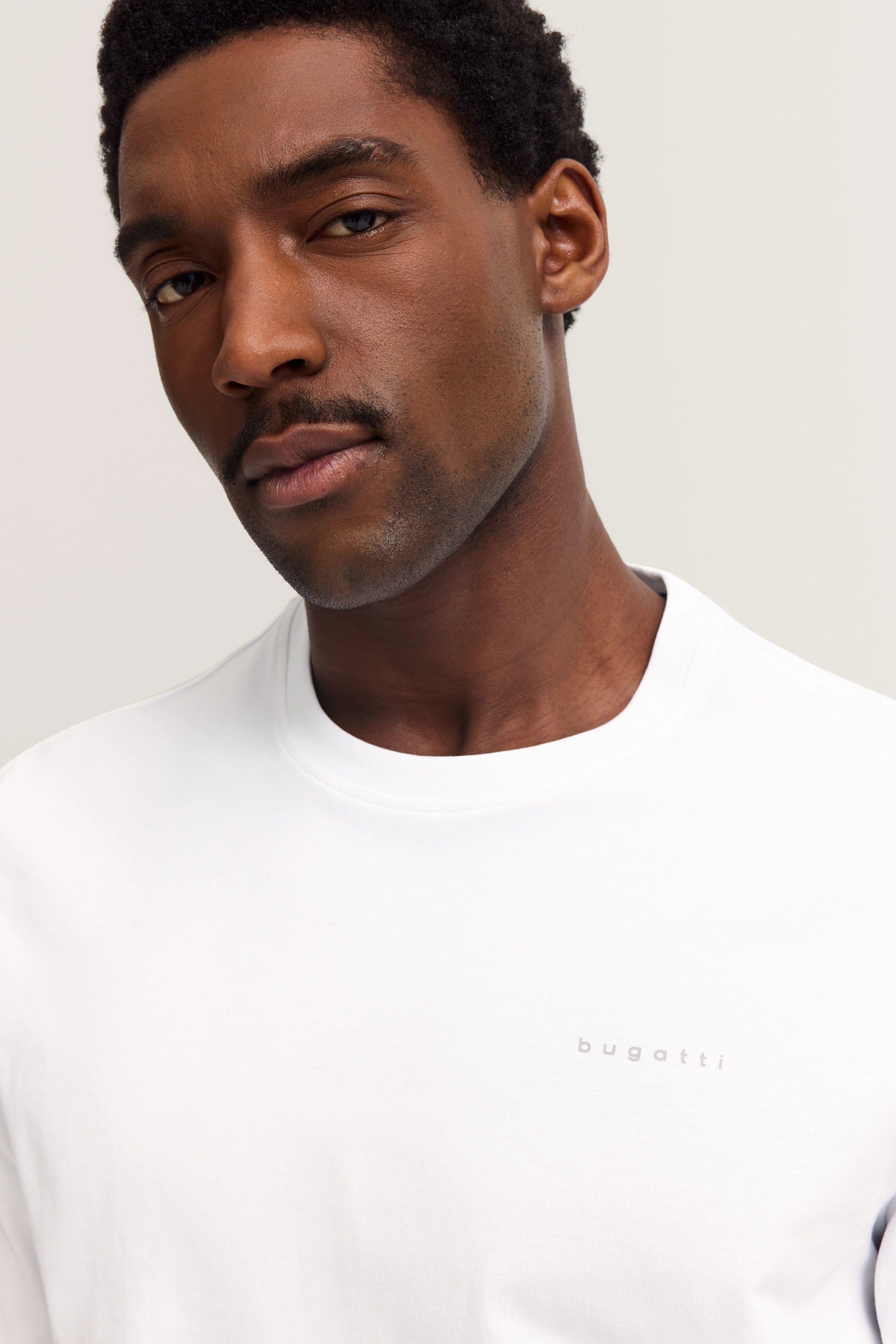 White bugatti T-shirt on model, bust shot, relaxed expression.