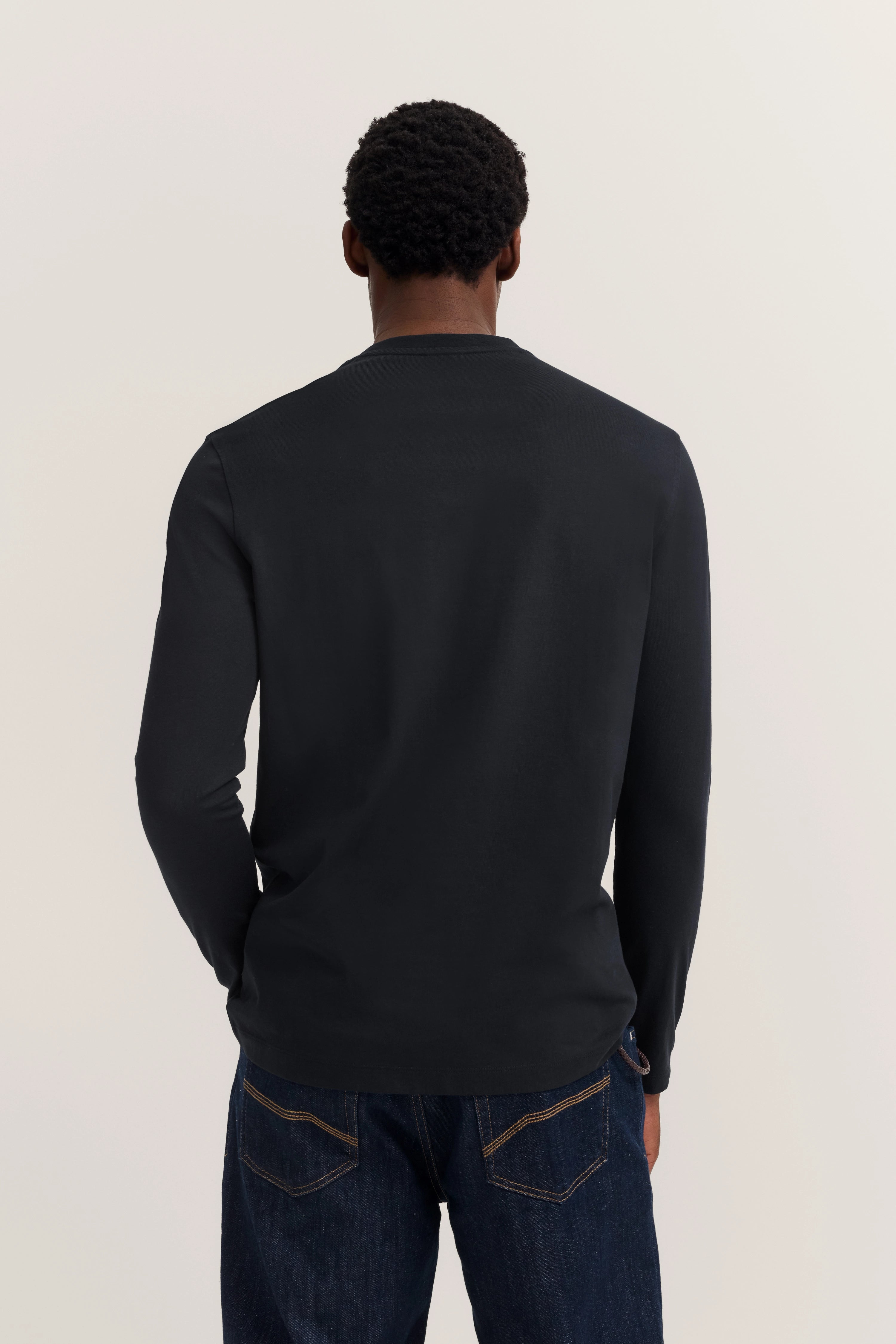 Schwarzes Langarmshirt und Jeans im legeren Modelbild, Rückenansicht, bugatti Stil.