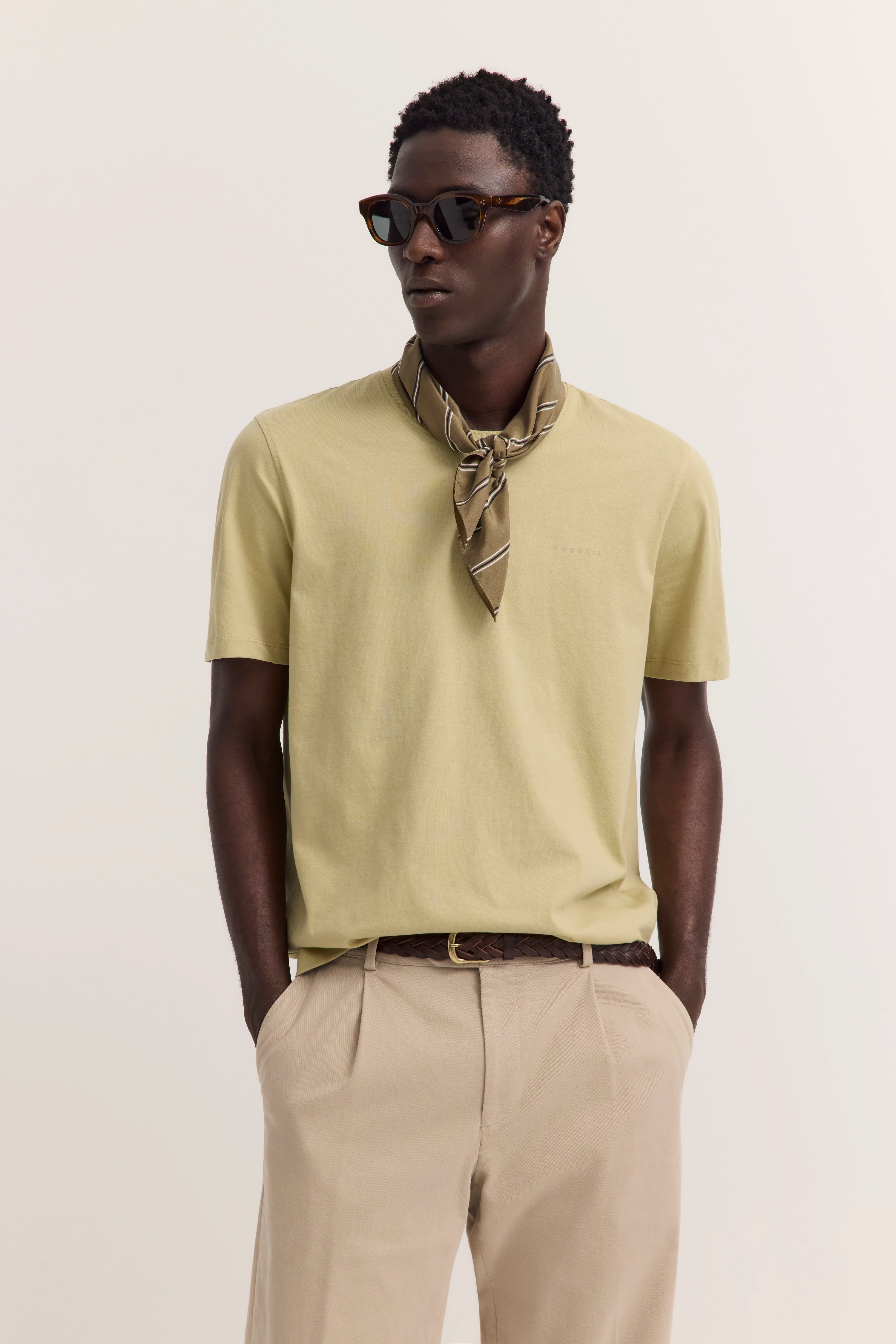 Model in beigefarbenem T-Shirt, heller Hose, gestreiftem Halstuch, Sonnenbrille