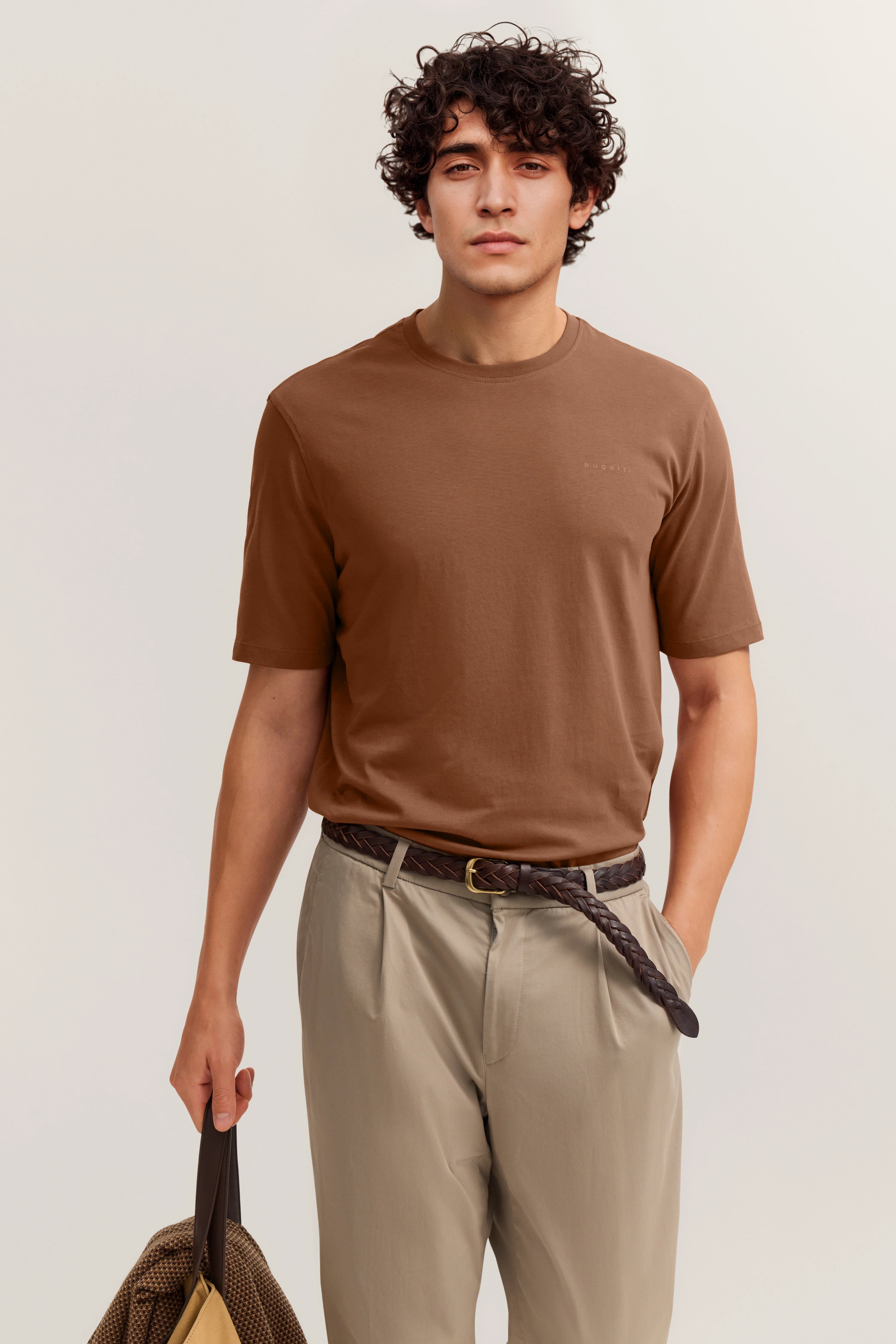 Braunes T-Shirt und beige Chinos von bugatti, Modelbild, lässige Haltung mit Tasche.