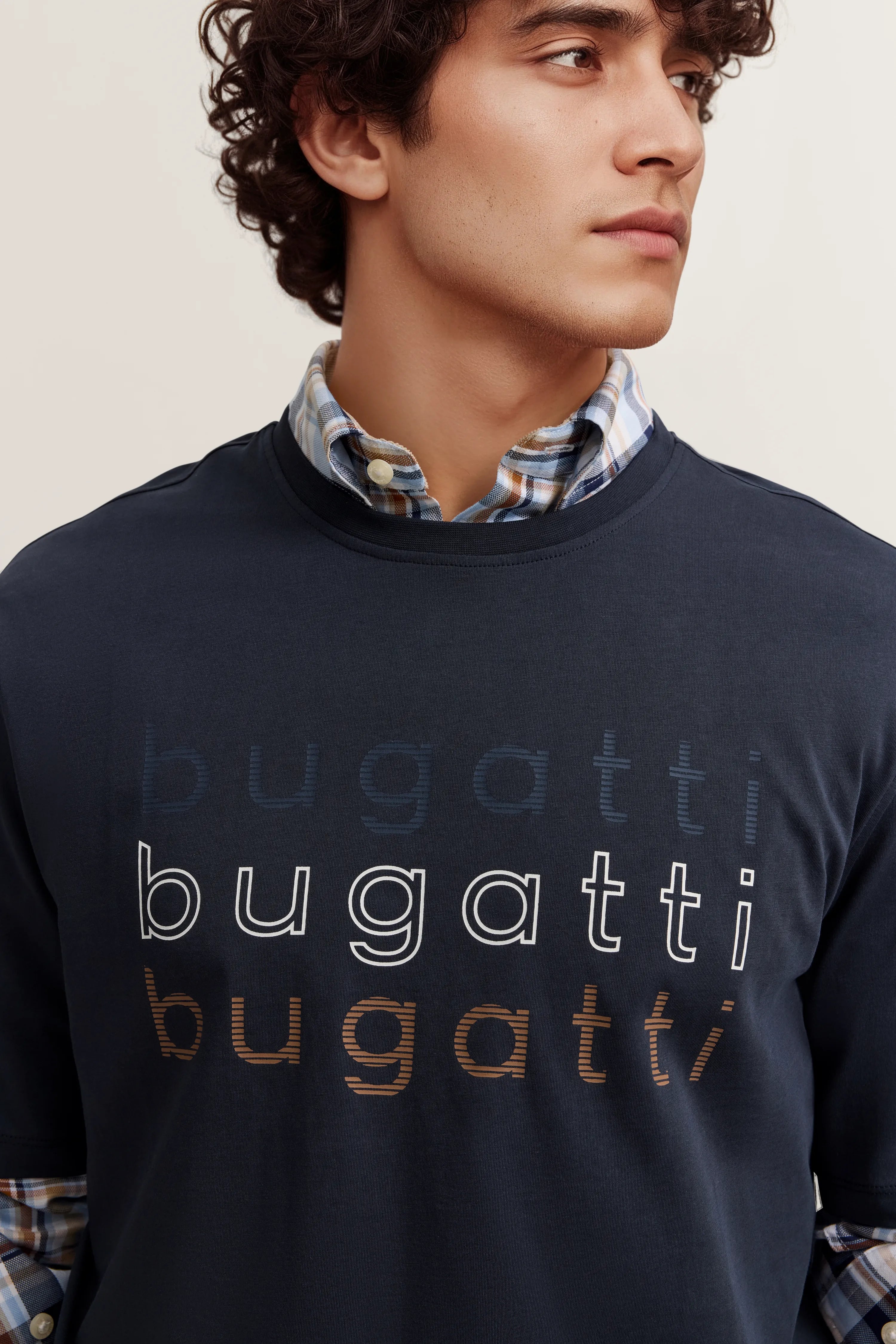 bugatti Shirt mit blauem Schriftzug über kariertem Hemd, Model in legerem Posing.
