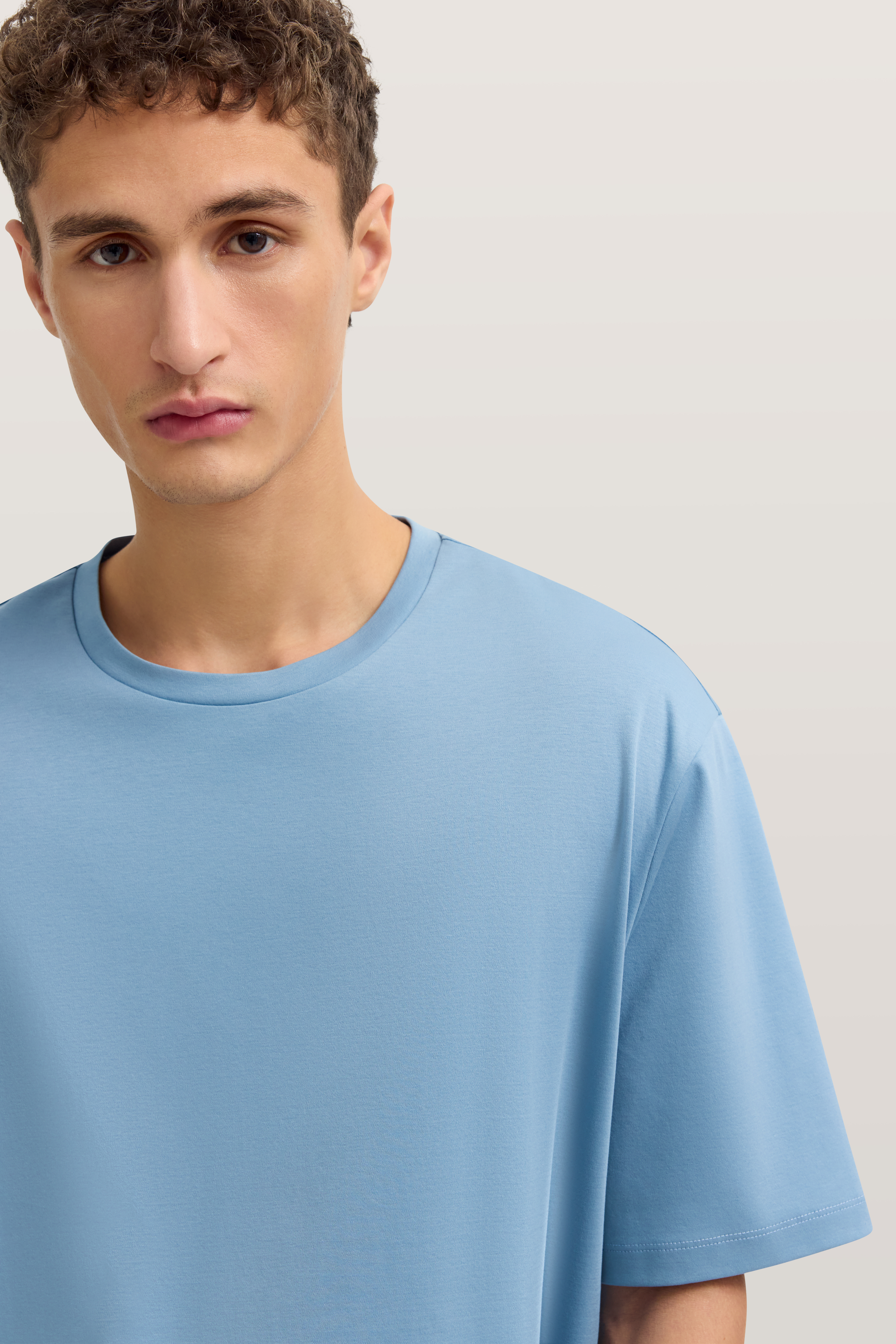 Model in hellblauem bugatti T-Shirt, legeres Büstenbild.