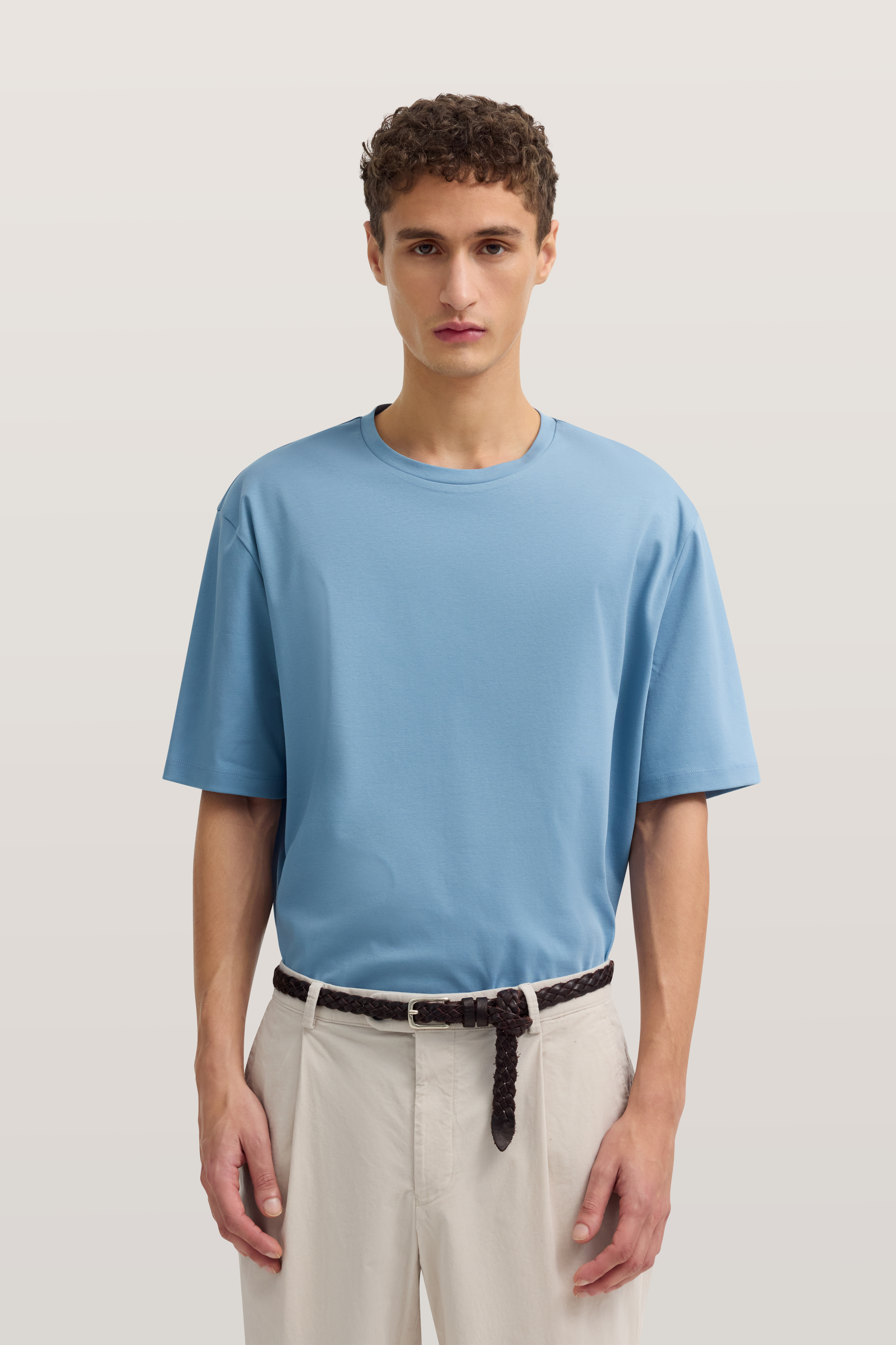 Blaues T-Shirt und beige Hose, Model im Stand, bugatti Stil und Eleganz.