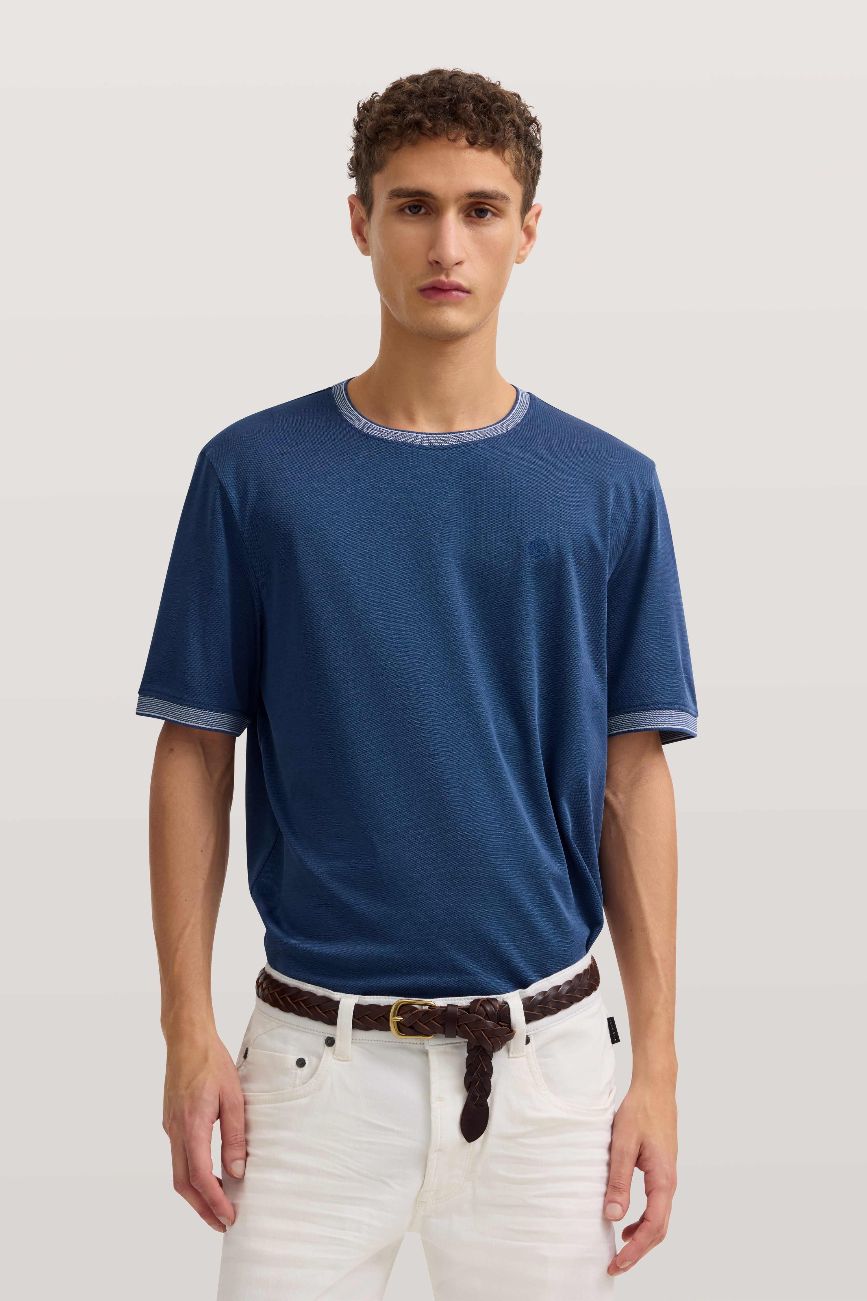 Modelbild: Lässig posierend in blauem T-Shirt und weißen Jeans, stilvoller Look von bugatti.