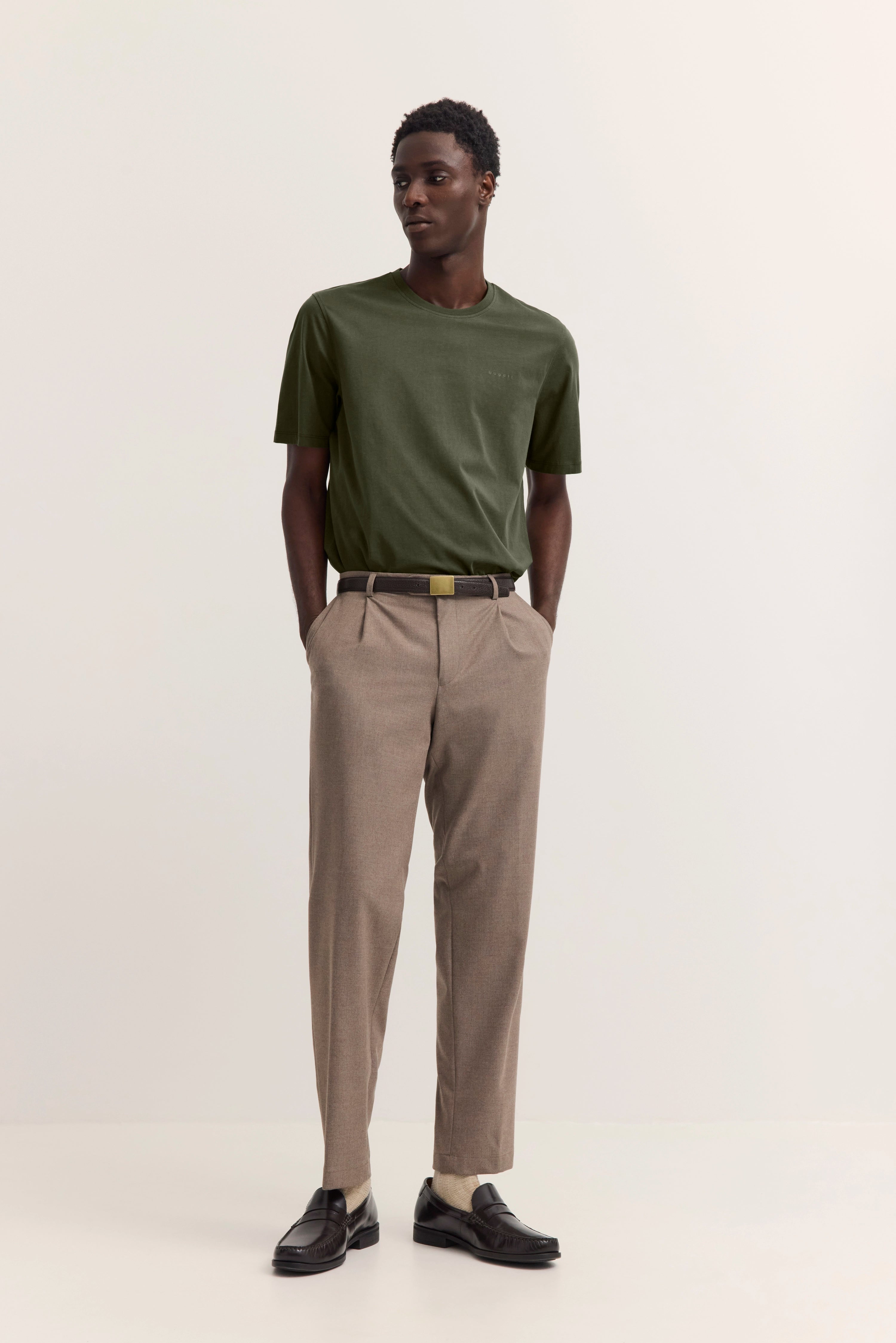 Grünes T-Shirt, beige Hose, schwarzer Gürtel