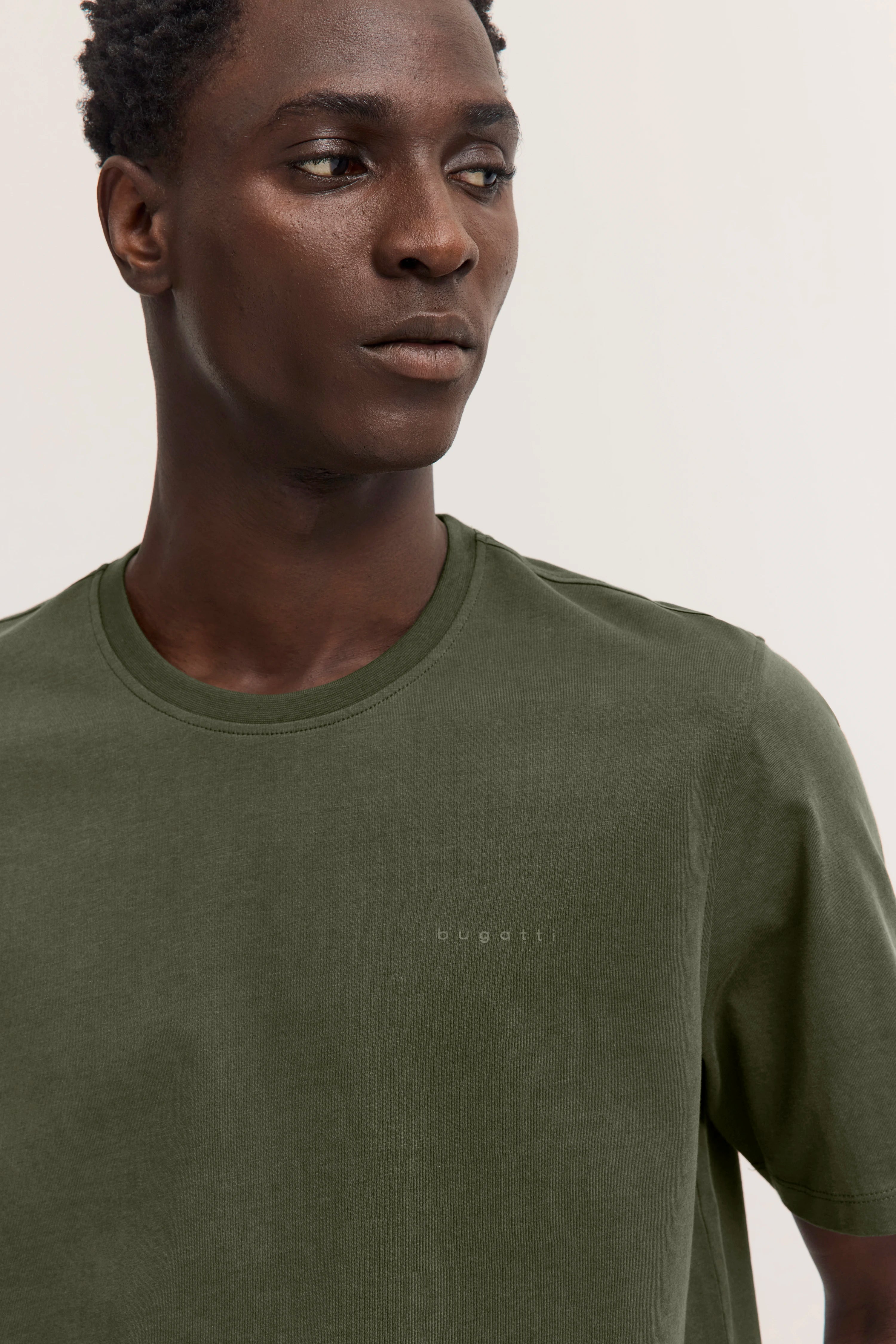 "bugatti olivgrünes T-Shirt Modellbild, entspannter Blick, stilvoll und zeitlos, Brustansicht."