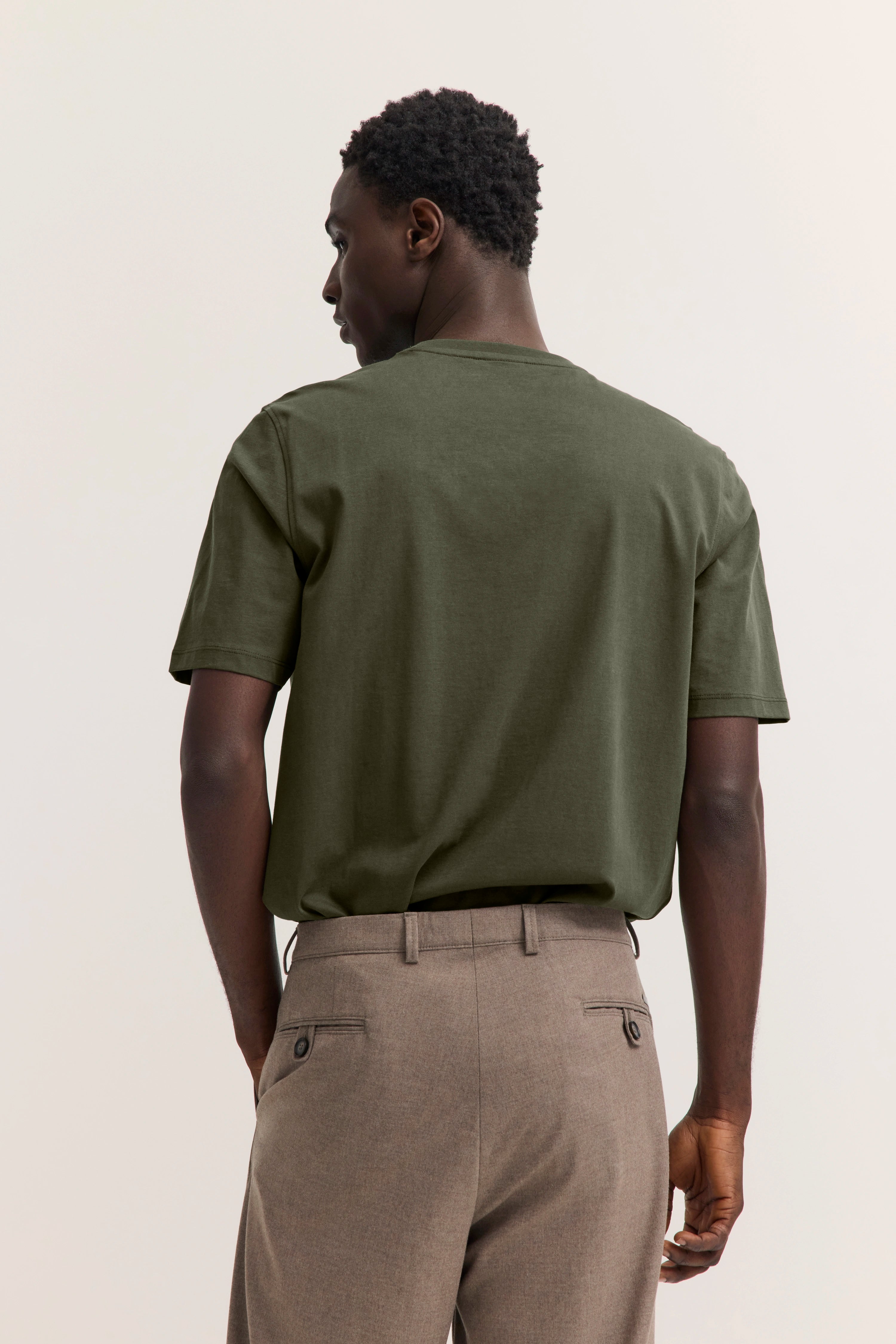 Grünes T-Shirt und beige Hose, Model von hinten, legeres Bild, bugatti Stil.