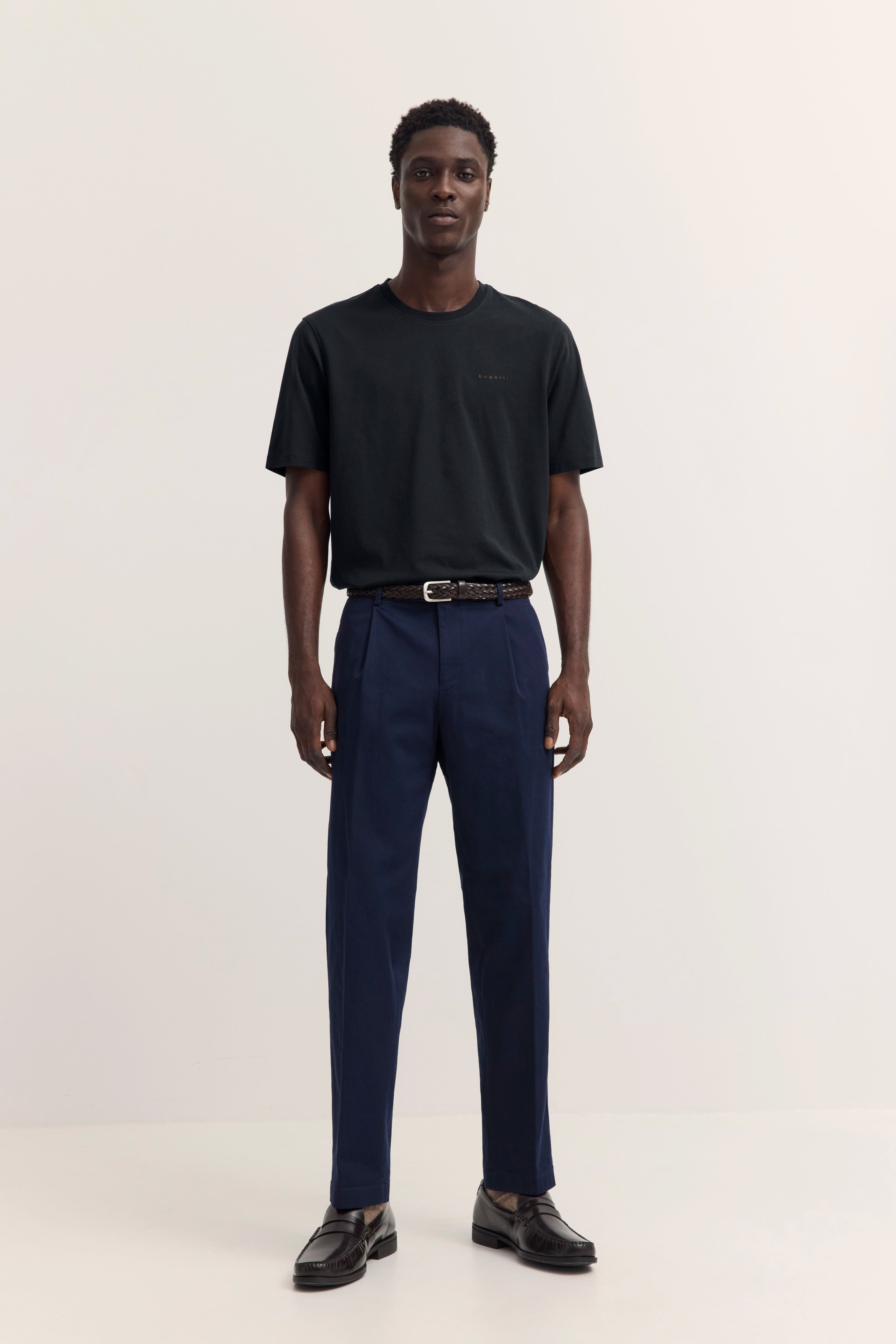 bugatti Modelbild: Schwarzes T-Shirt, blaue Hose, schwarze Schuhe, entspanntes Stehen.
