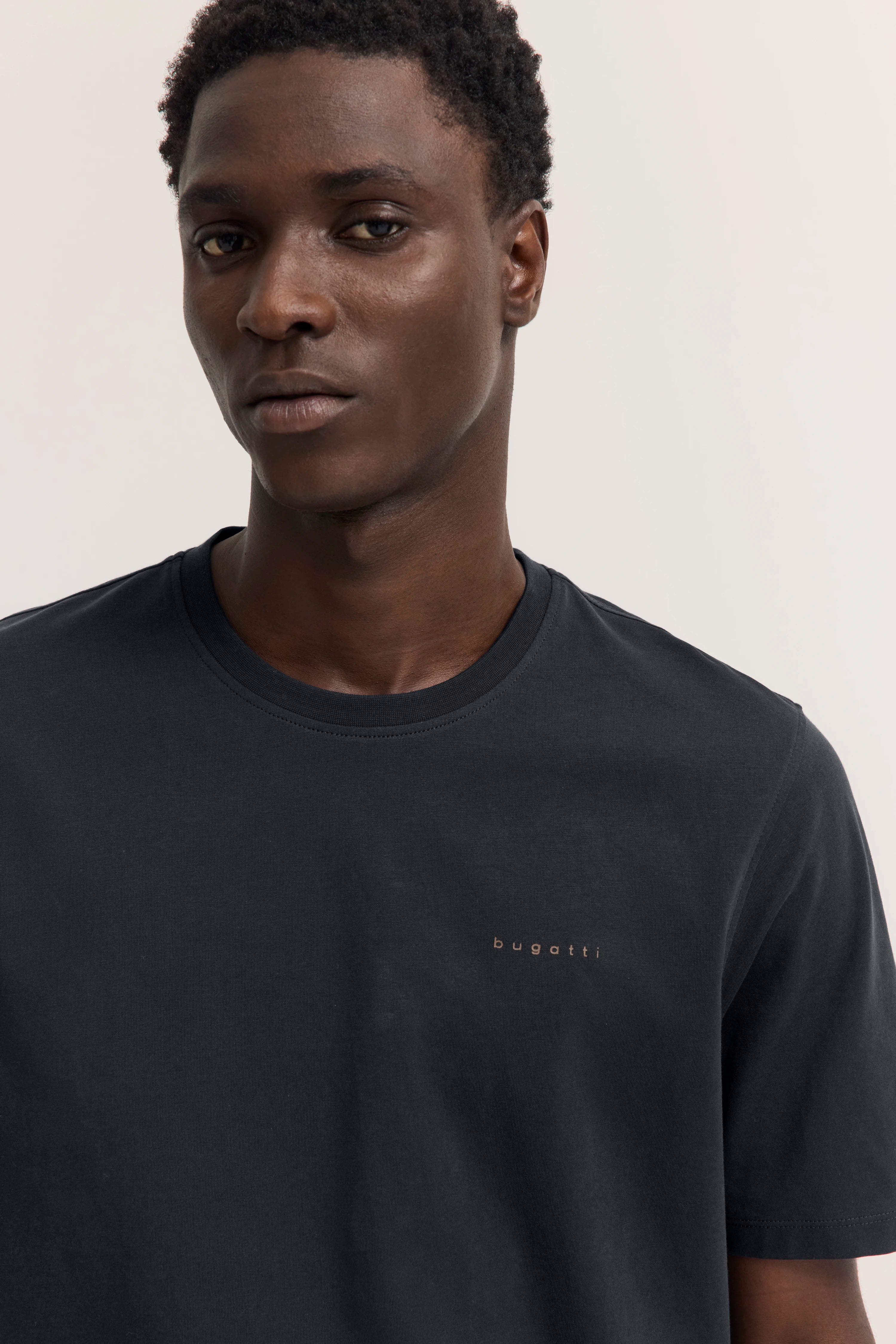 Schwarzes bugatti T-Shirt, Modelbild, entspannte Pose, zeitloser Stil.