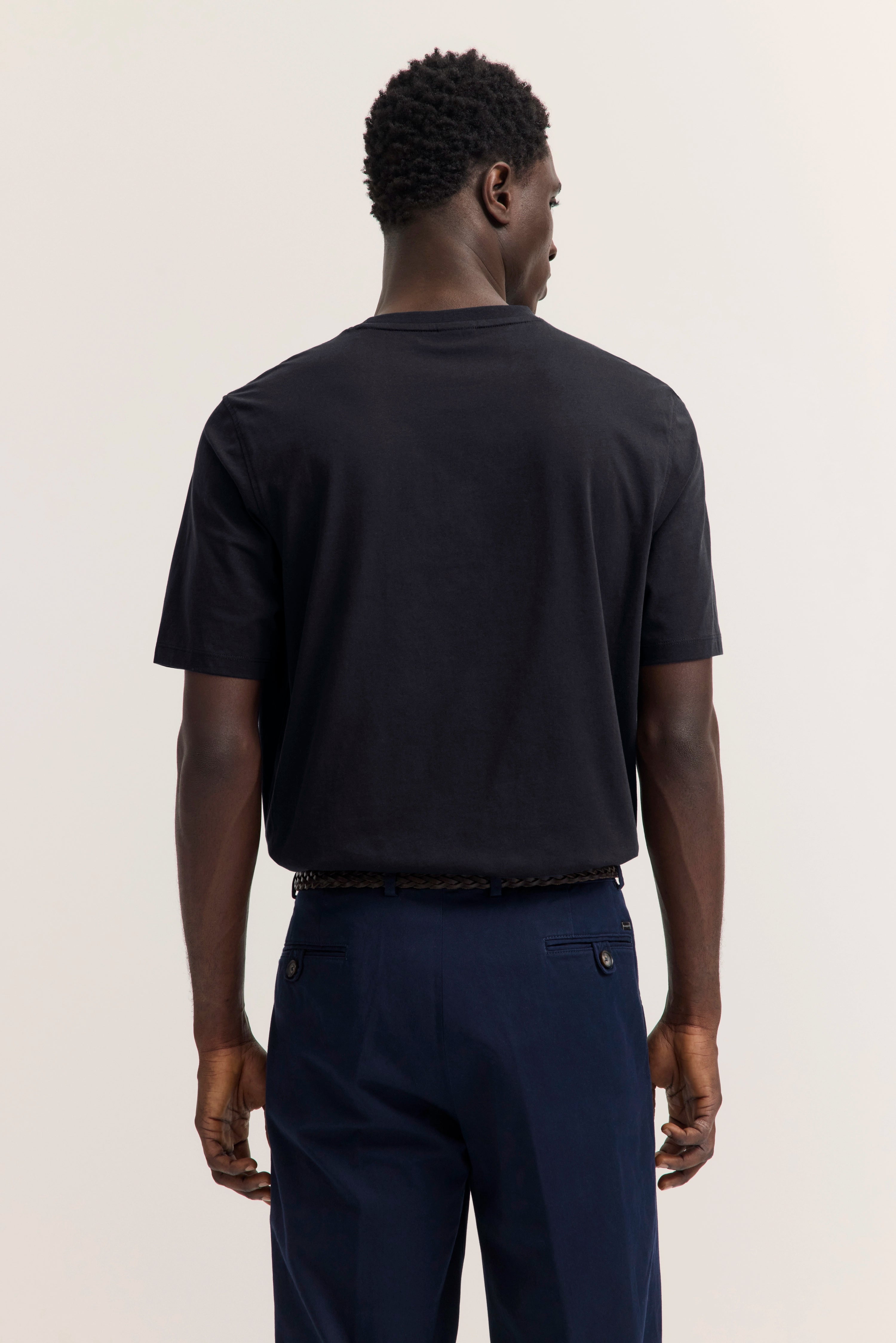 Schwarzes T-Shirt und blaue Hose, Rückansicht eines Modells, legeres Outfit von bugatti.
