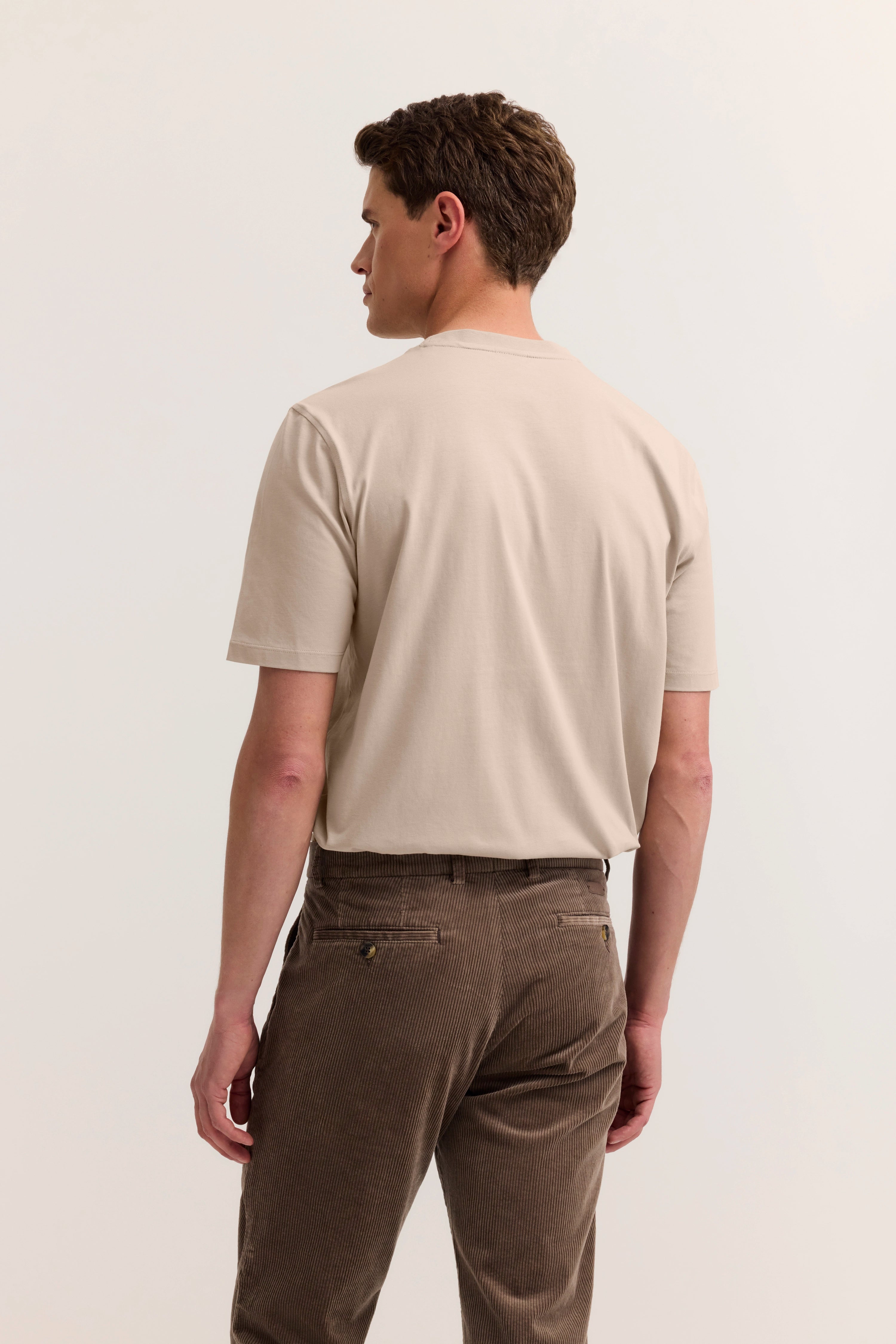 Beiges T-Shirt und braune Hose, Modelrückansicht, entspanntes Posing.