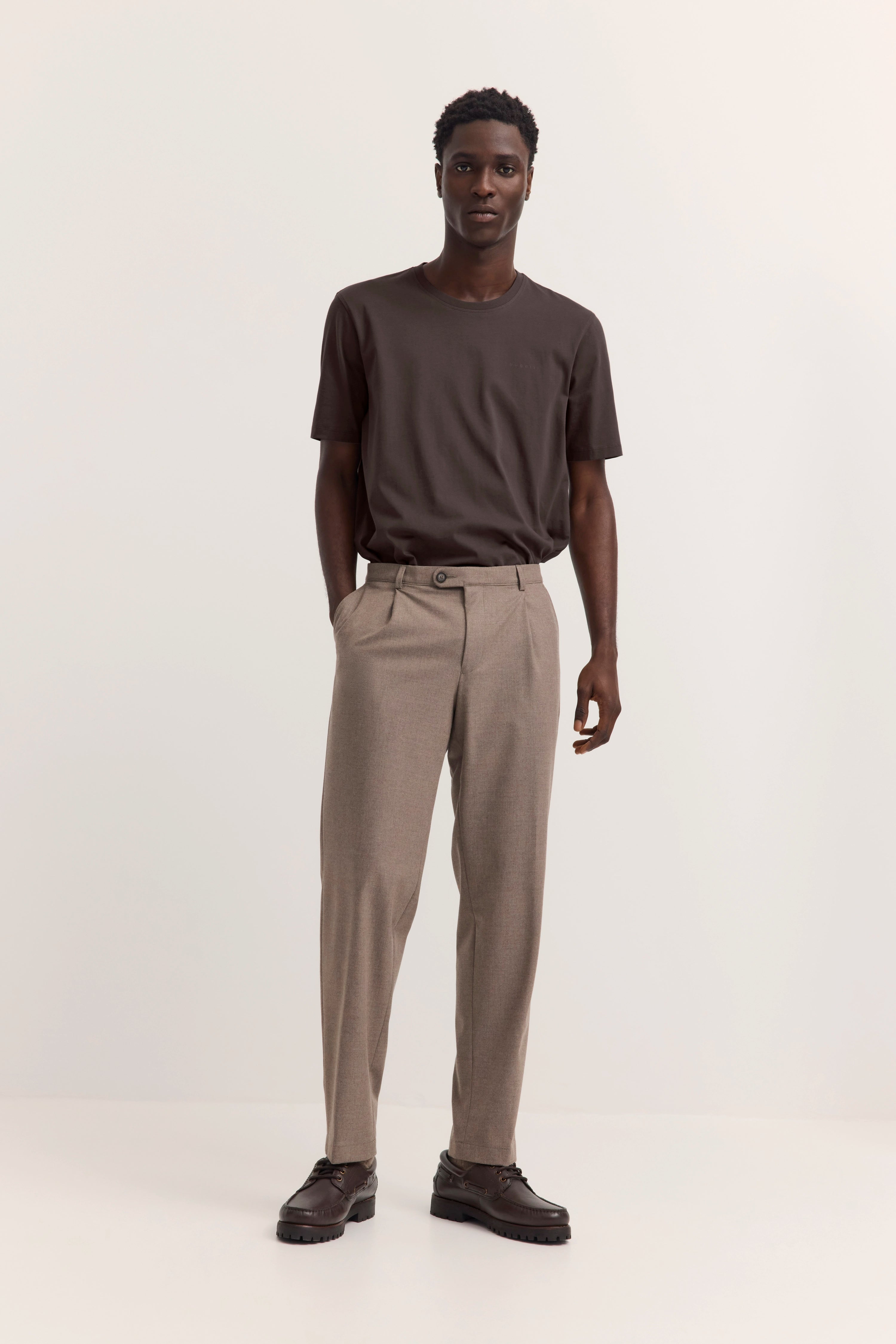 bugatti Model in braunem Shirt und beigefarbenen Hosen, leger stehend.