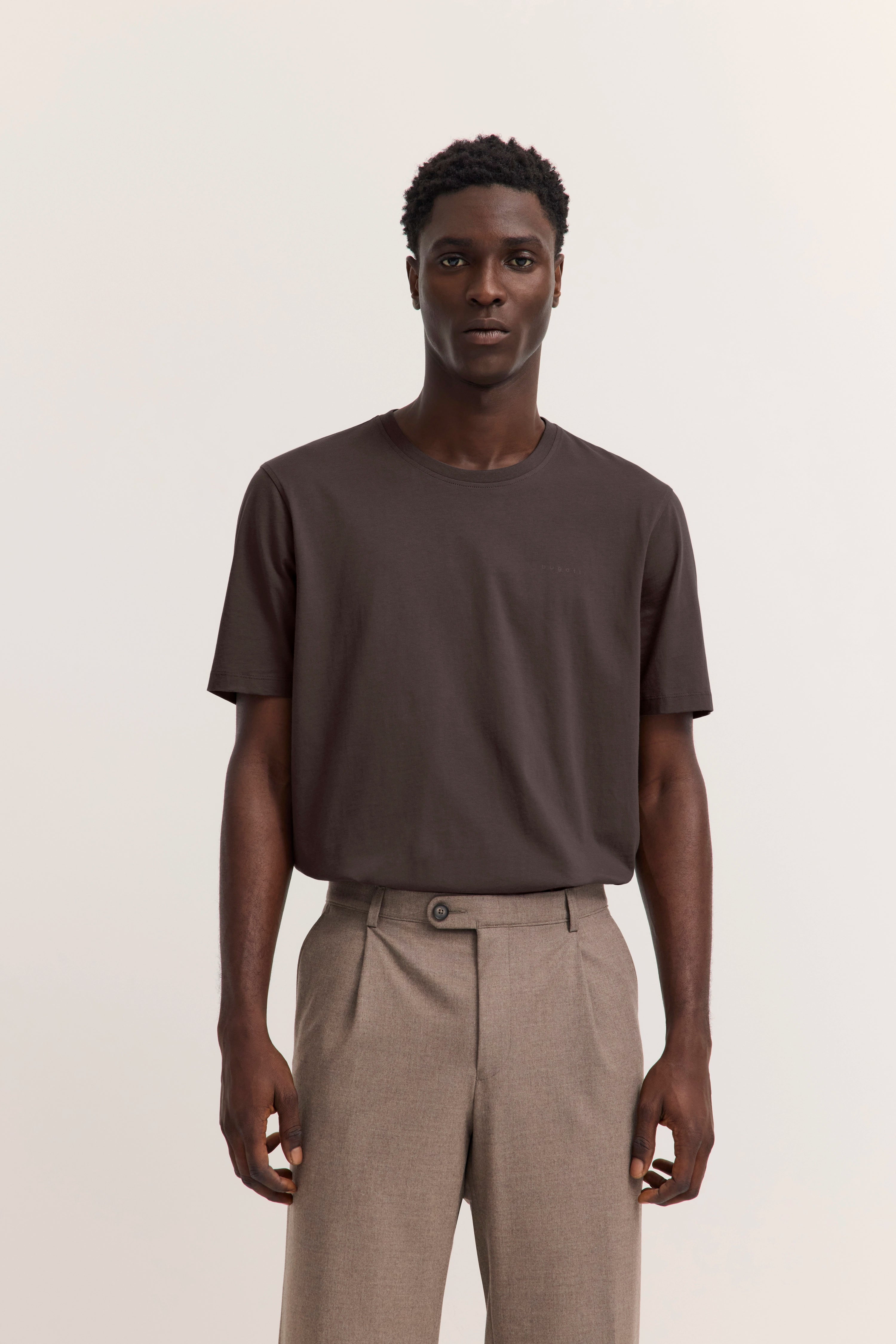 Braunes T-Shirt und beige Hose, Modelbild, entspannte Pose.