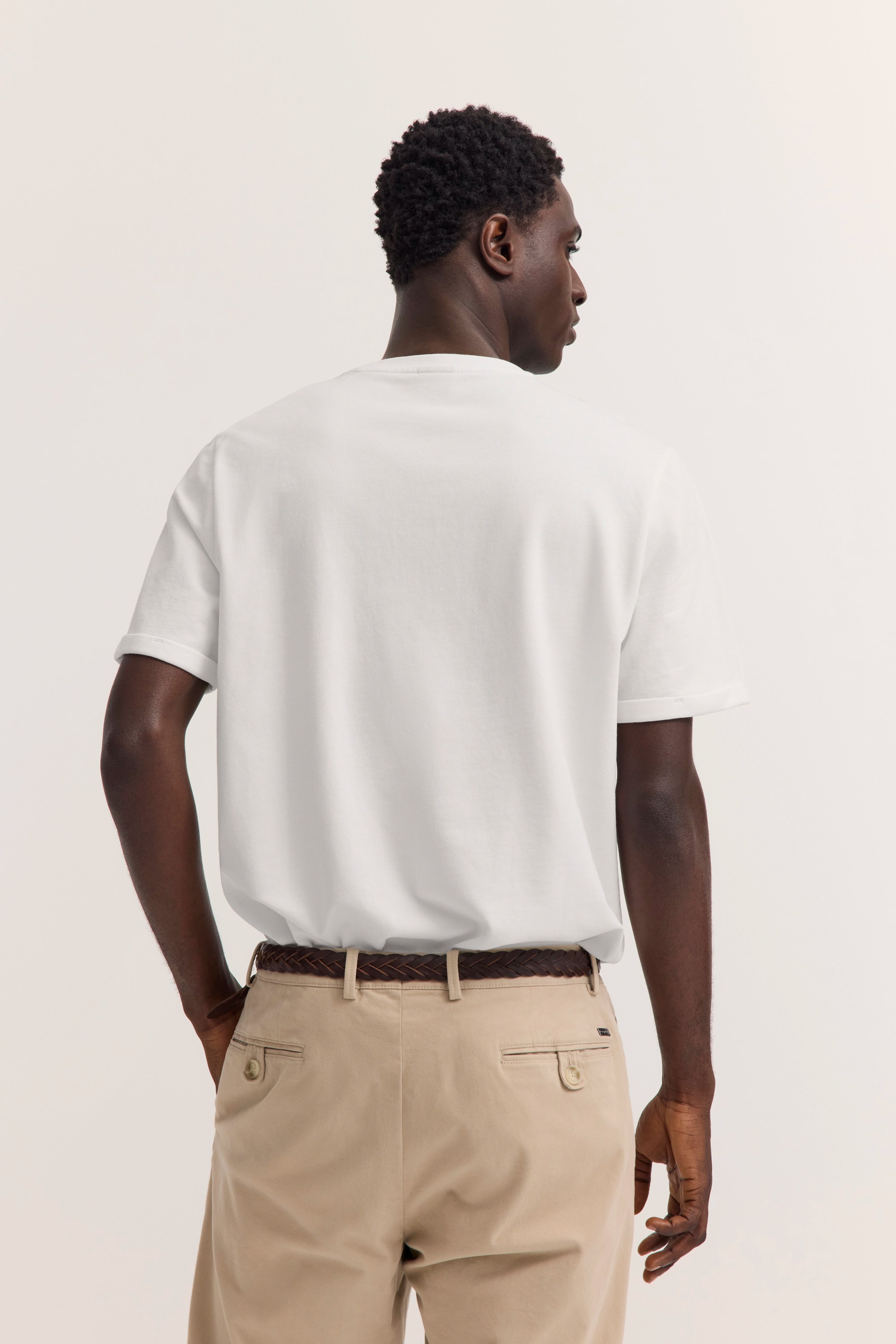 Weißes T-Shirt und beige Chinos, Rückansicht Model, legeres Posing, bugatti Stil.