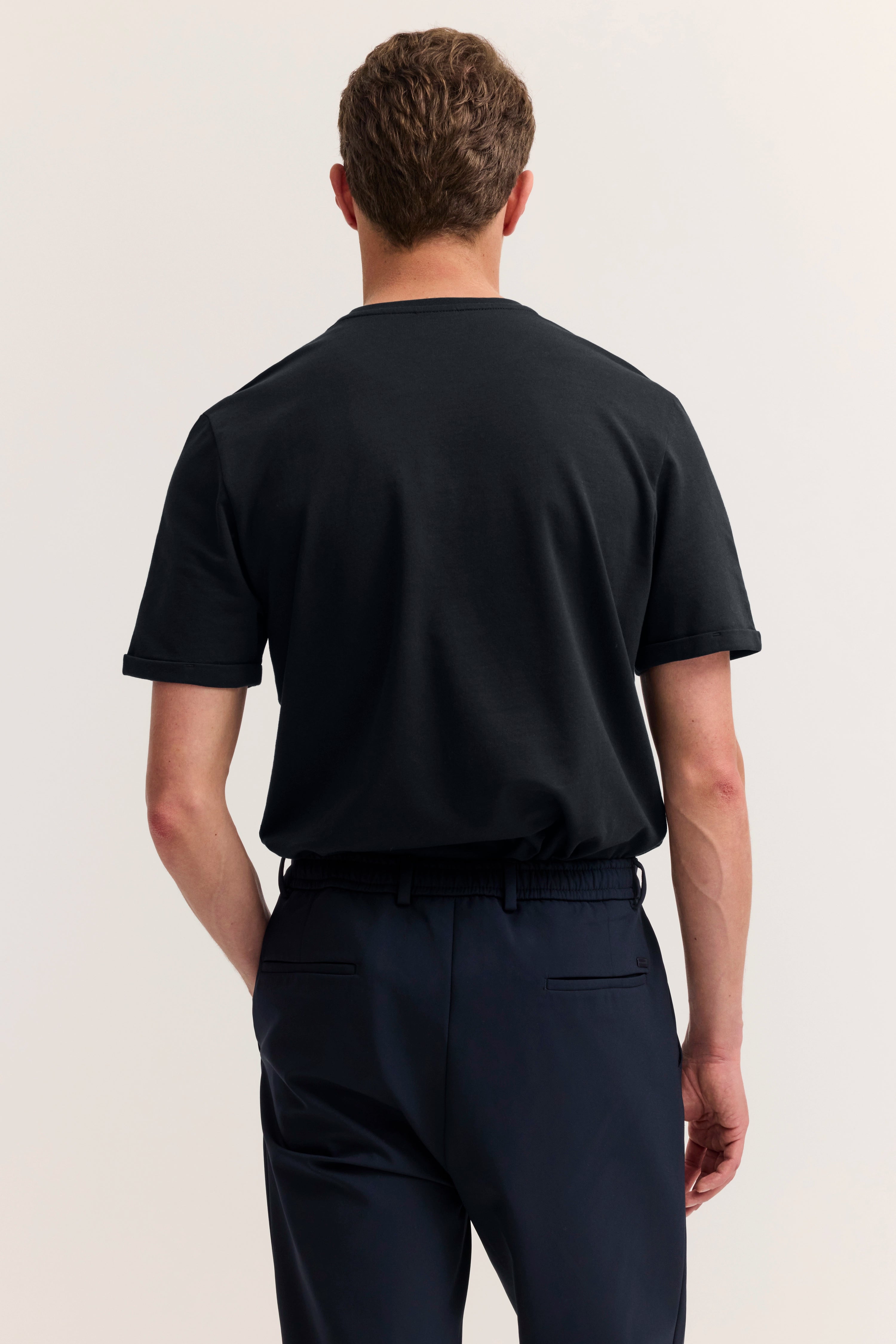 Schwarzes T-Shirt und dunkelblaue Hose, legeres Modelbild, Rückansicht.