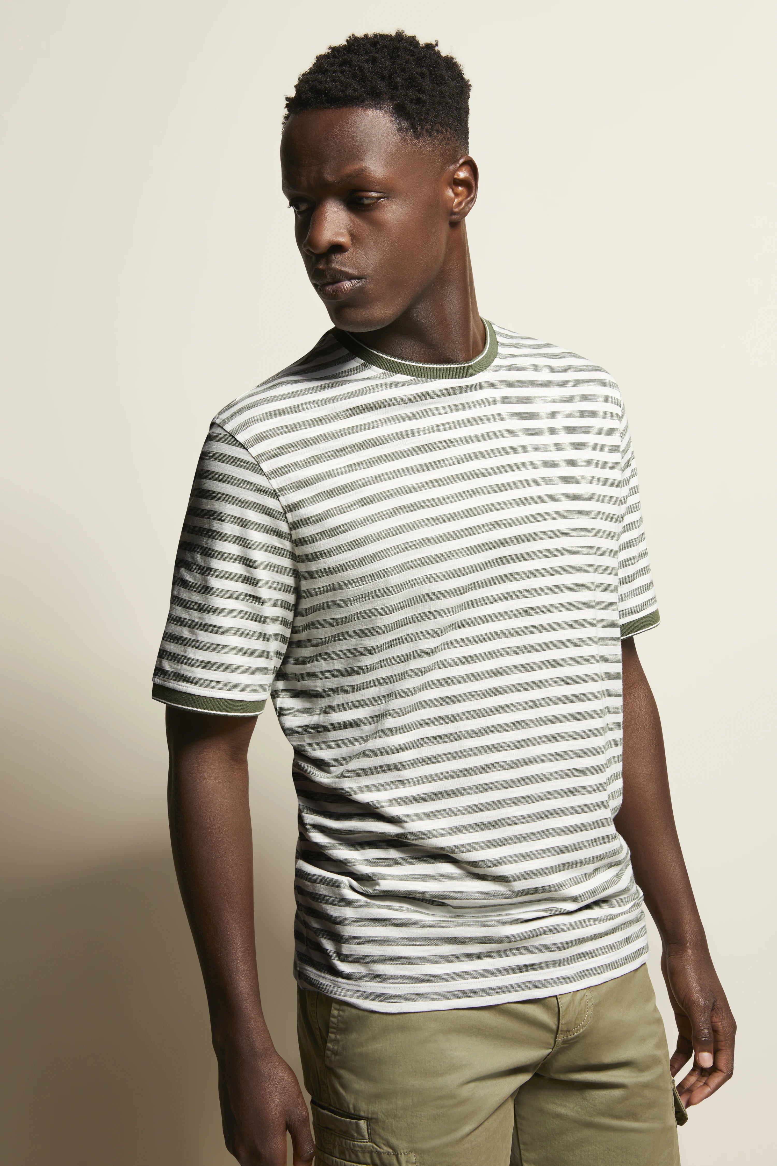 White-green striped T-shirt, olive green shorts, model in relaxed pose, exuding bugatti's Italian-inspired elegance.
