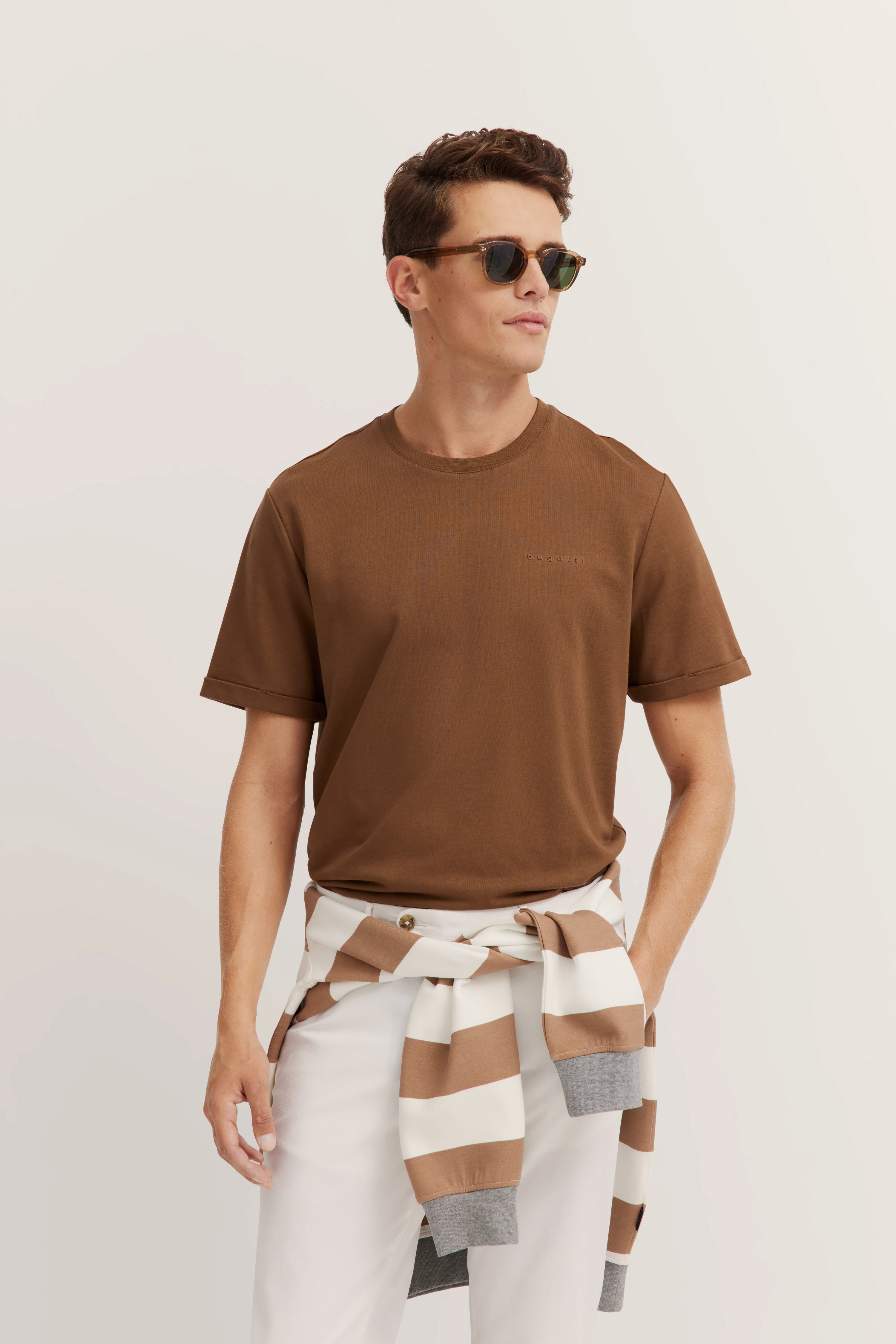 Brown bugatti T-shirt, white-brown striped sweater around waist, white background, model with sunglasses.
