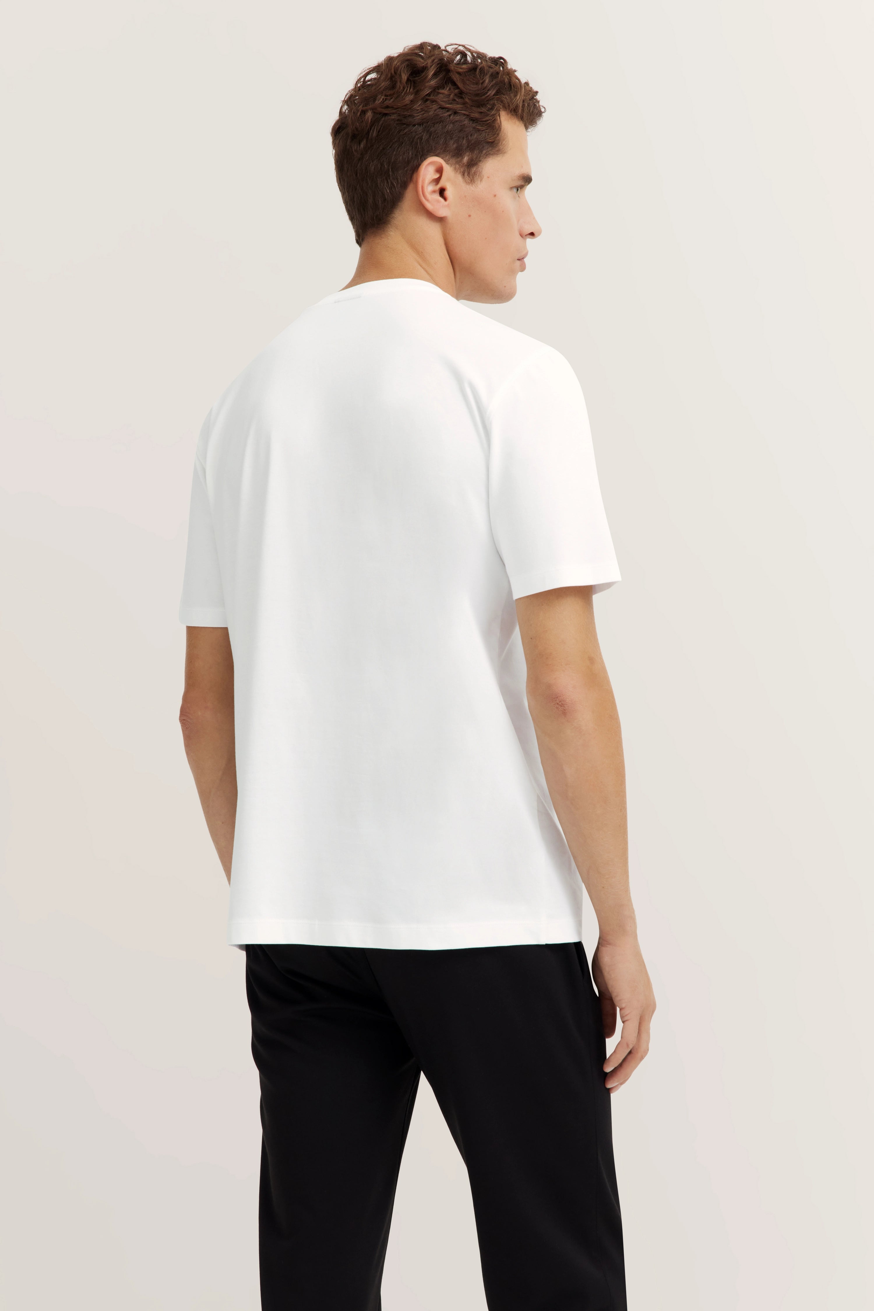 bugatti Model in weißem T-Shirt und schwarzen Hosen, Rückansicht, entspannte Pose.