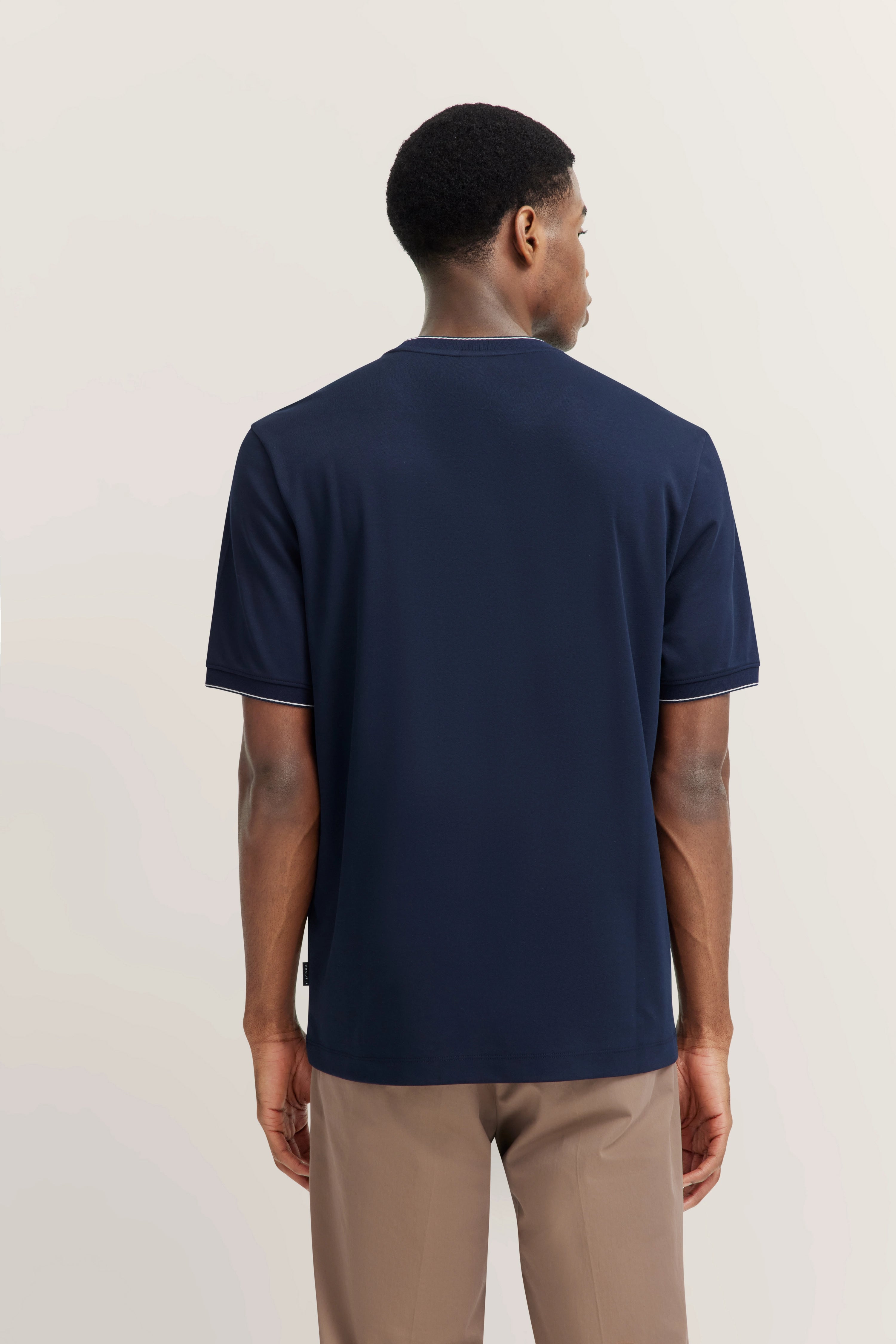 Navy T-shirt by bugatti, back view on model, paired with beige trousers.