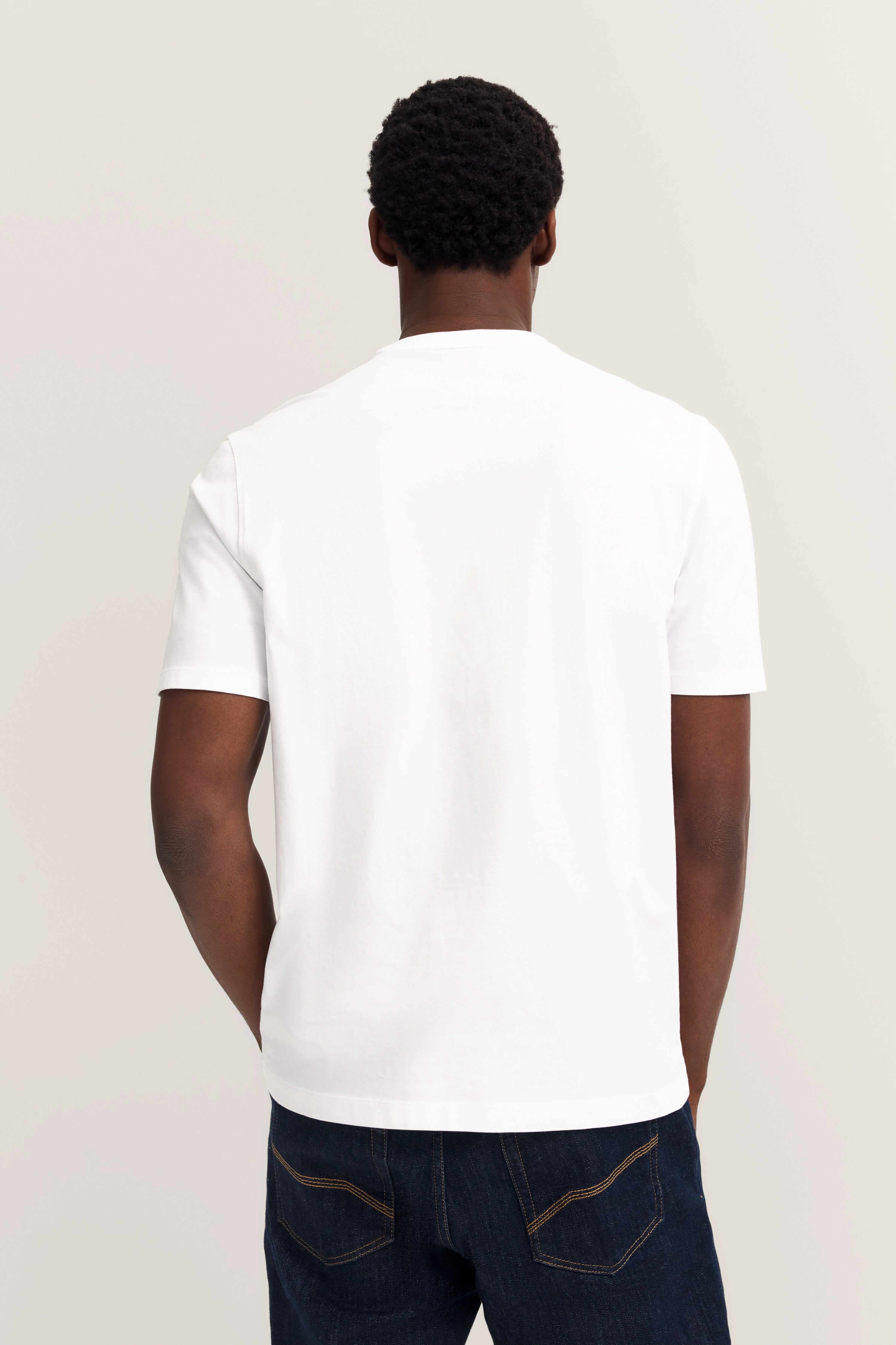 Weißes T-Shirt, Rückansicht, dunkelblaue Jeans, legeres Modelbild.