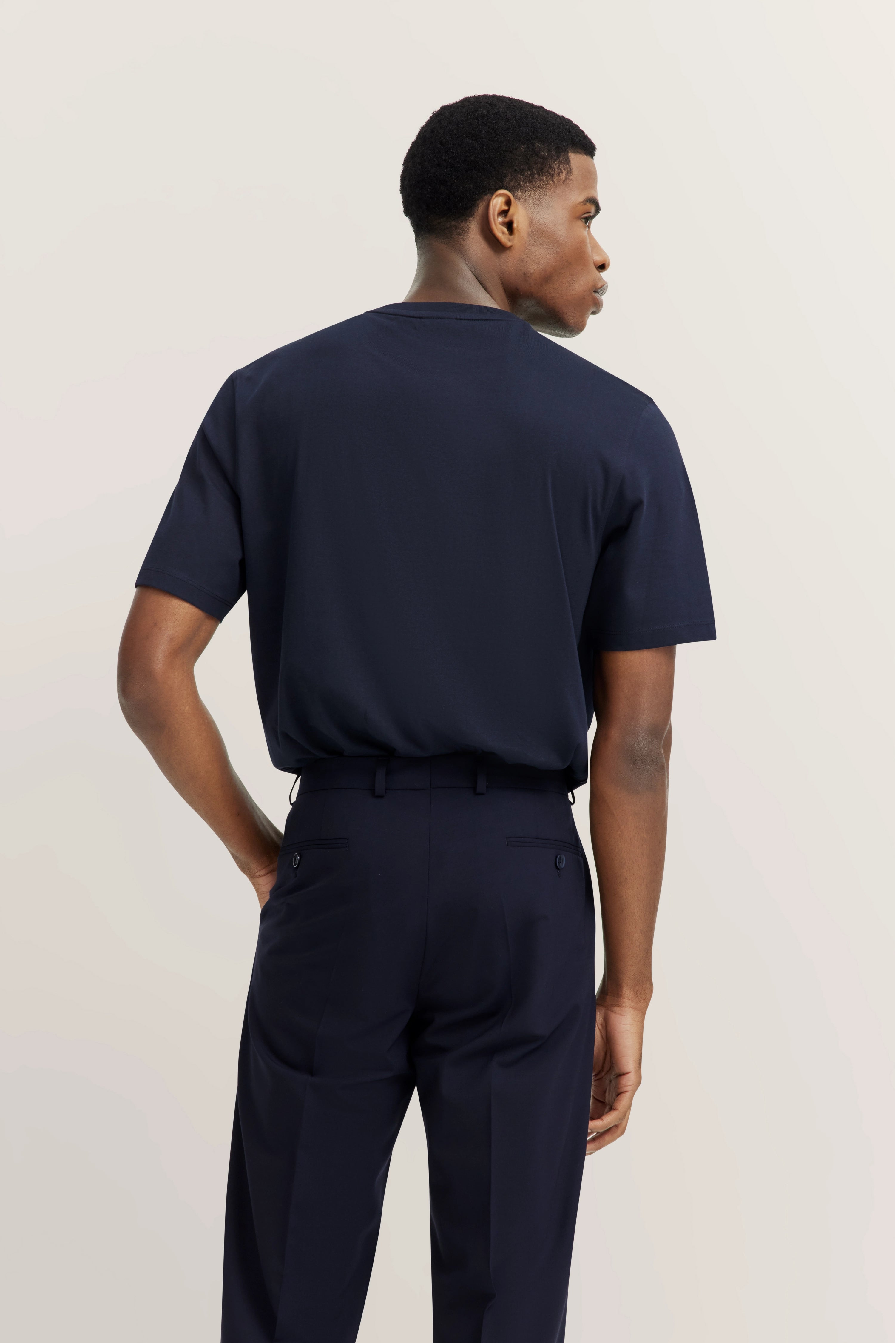 Model in dunkelblauem T-Shirt und Hose von bugatti, Rückansicht, entspanntes Posing.