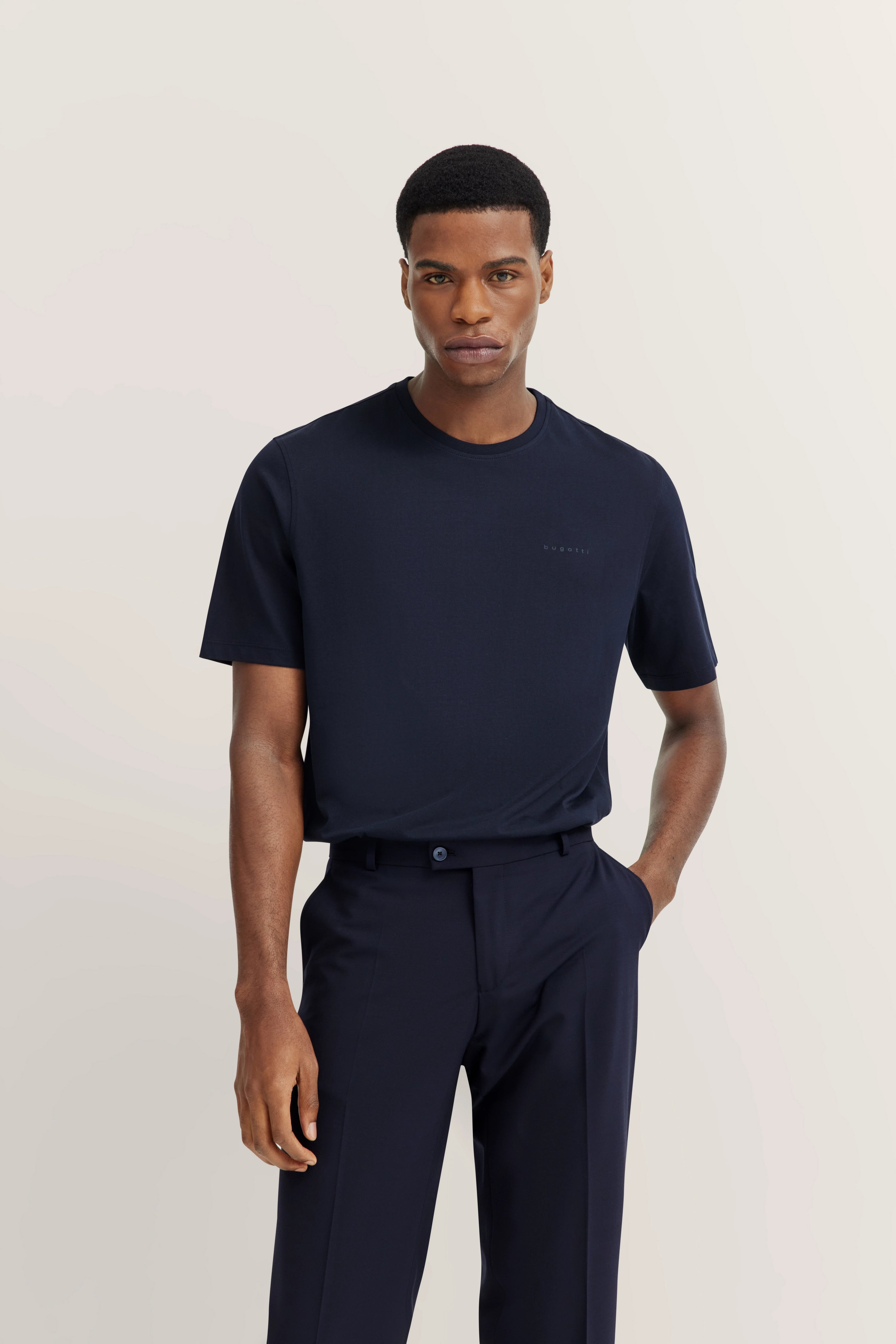 Model in navy bugatti T-shirt and trousers, relaxed pose, hands in pockets.