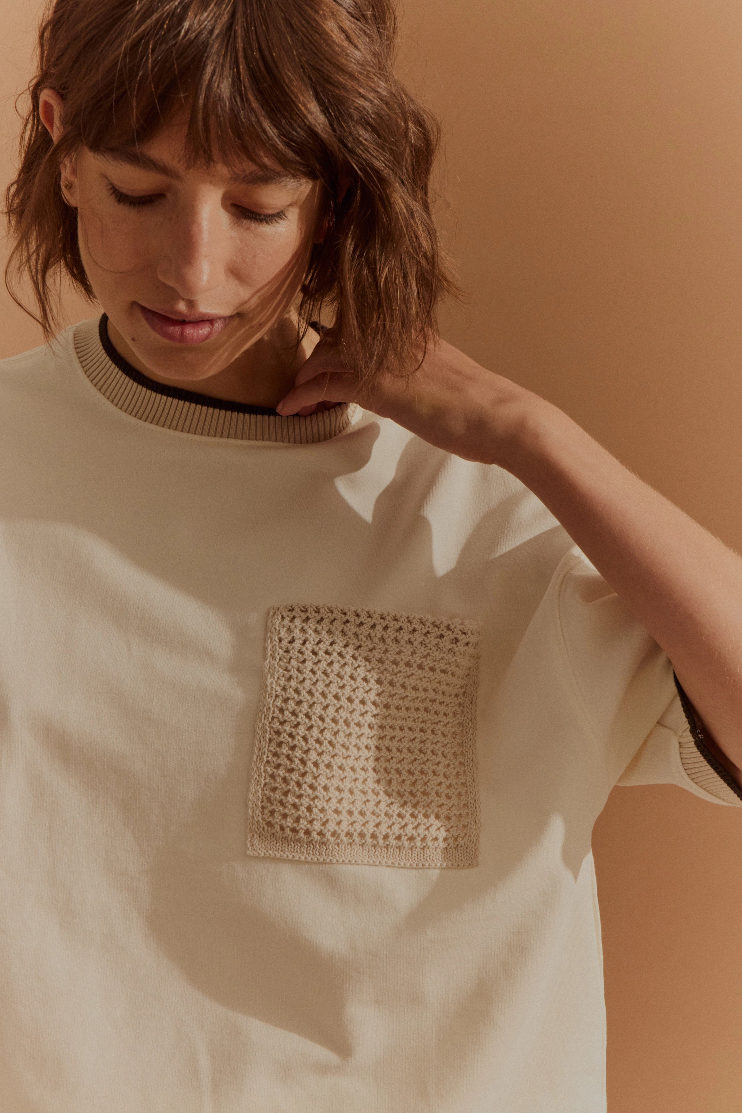 Büstenbild von cremefarbenem bugatti Pullover mit gestrickter Tasche, entspanntes Posing.