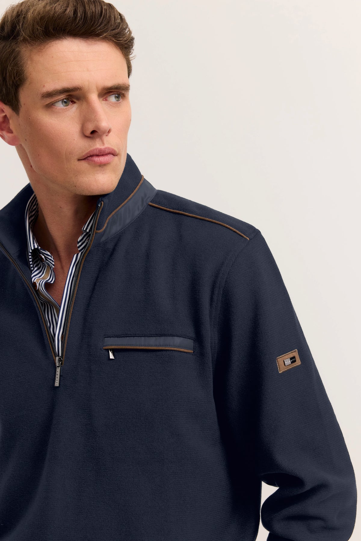 Navy Pullover von bugatti mit Stehkragen, braunen Akzenten und Zipper. Model seitlich blickend.
