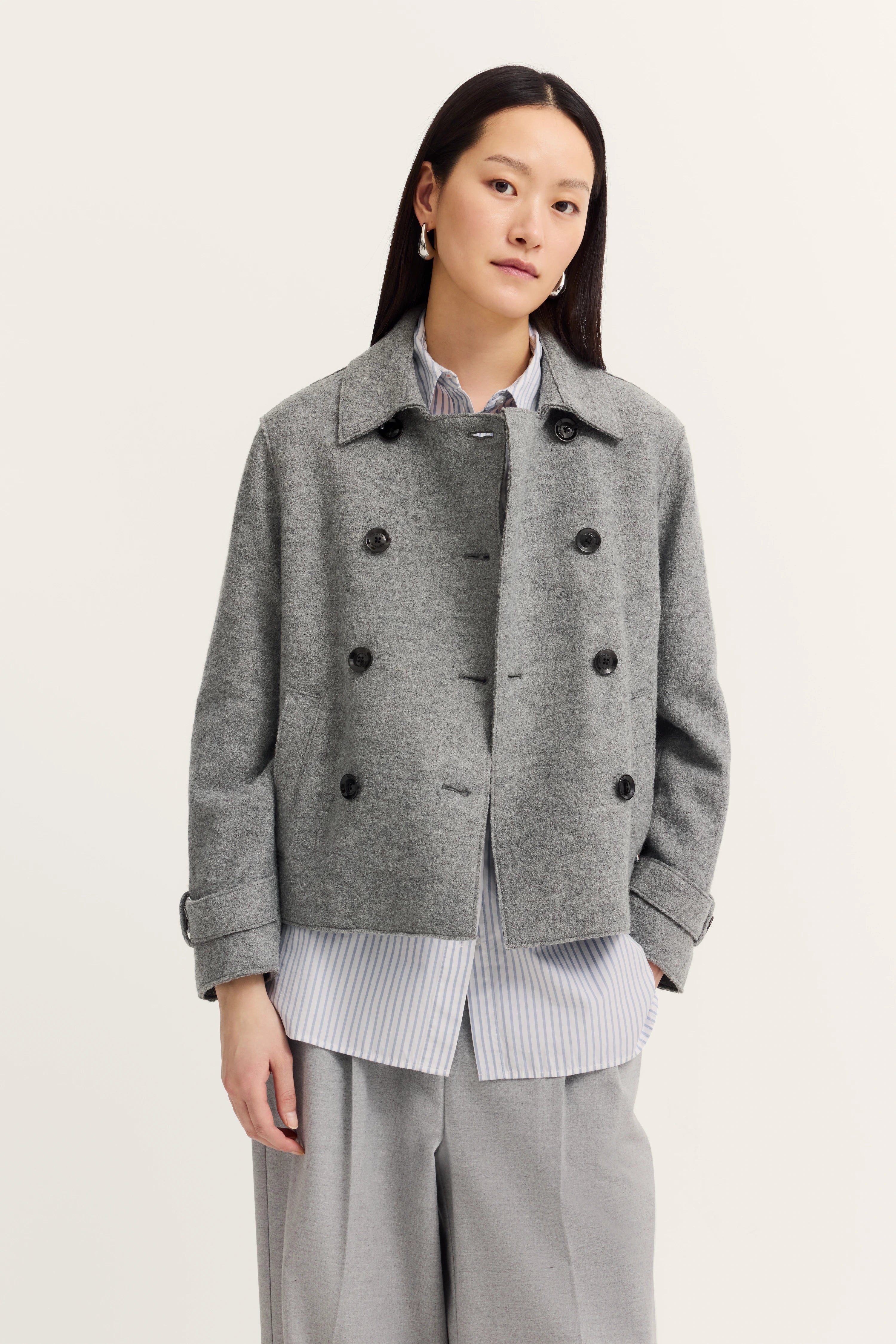 Grauer Mantel und gestreiftes Hemd auf Modelbild, entspanntes Posing, bugatti Stil.