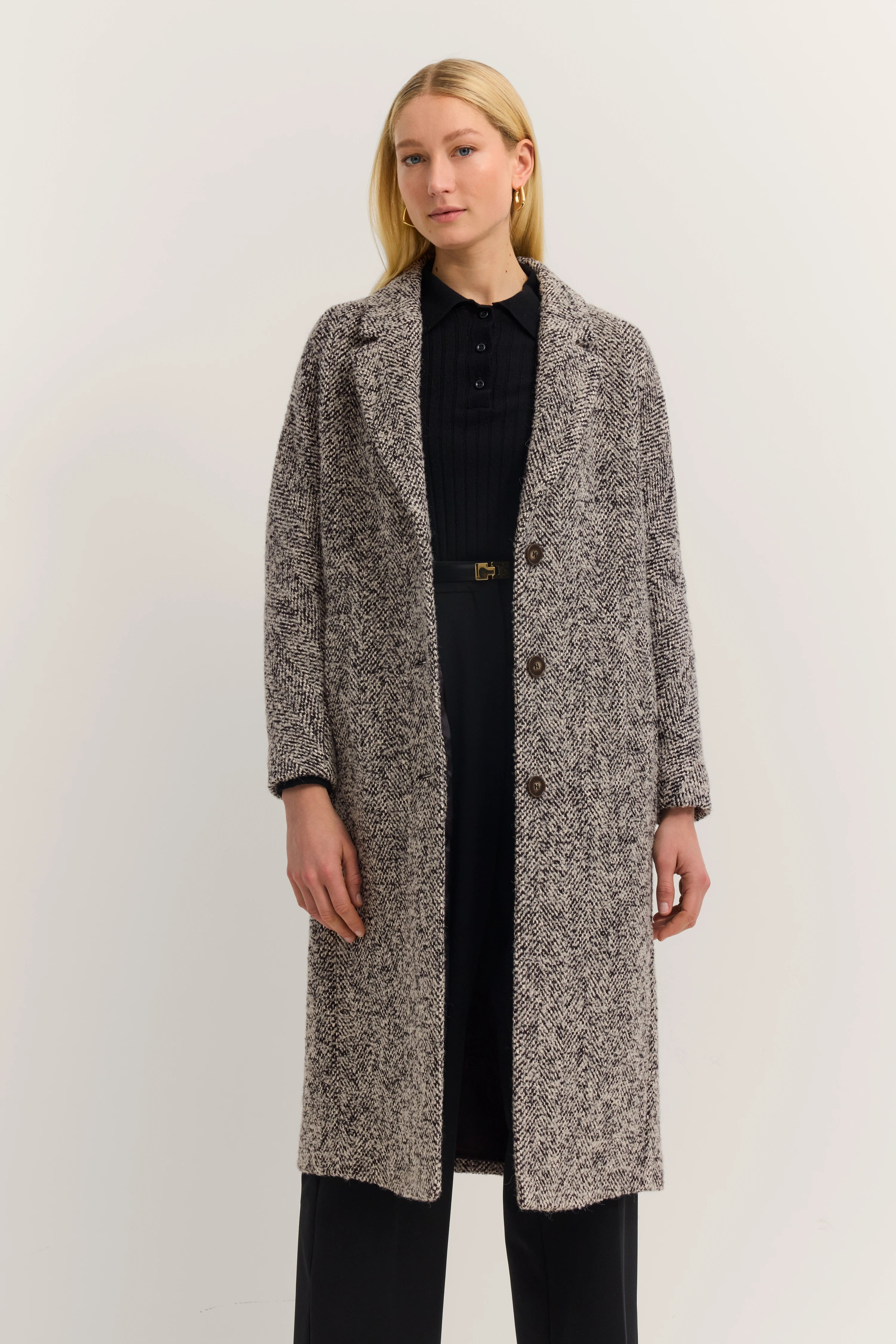 Grauer Herringbone-Mantel von bugatti, Modelbild, legeres Posing, schwarzer Pullover, schwarze Hose.