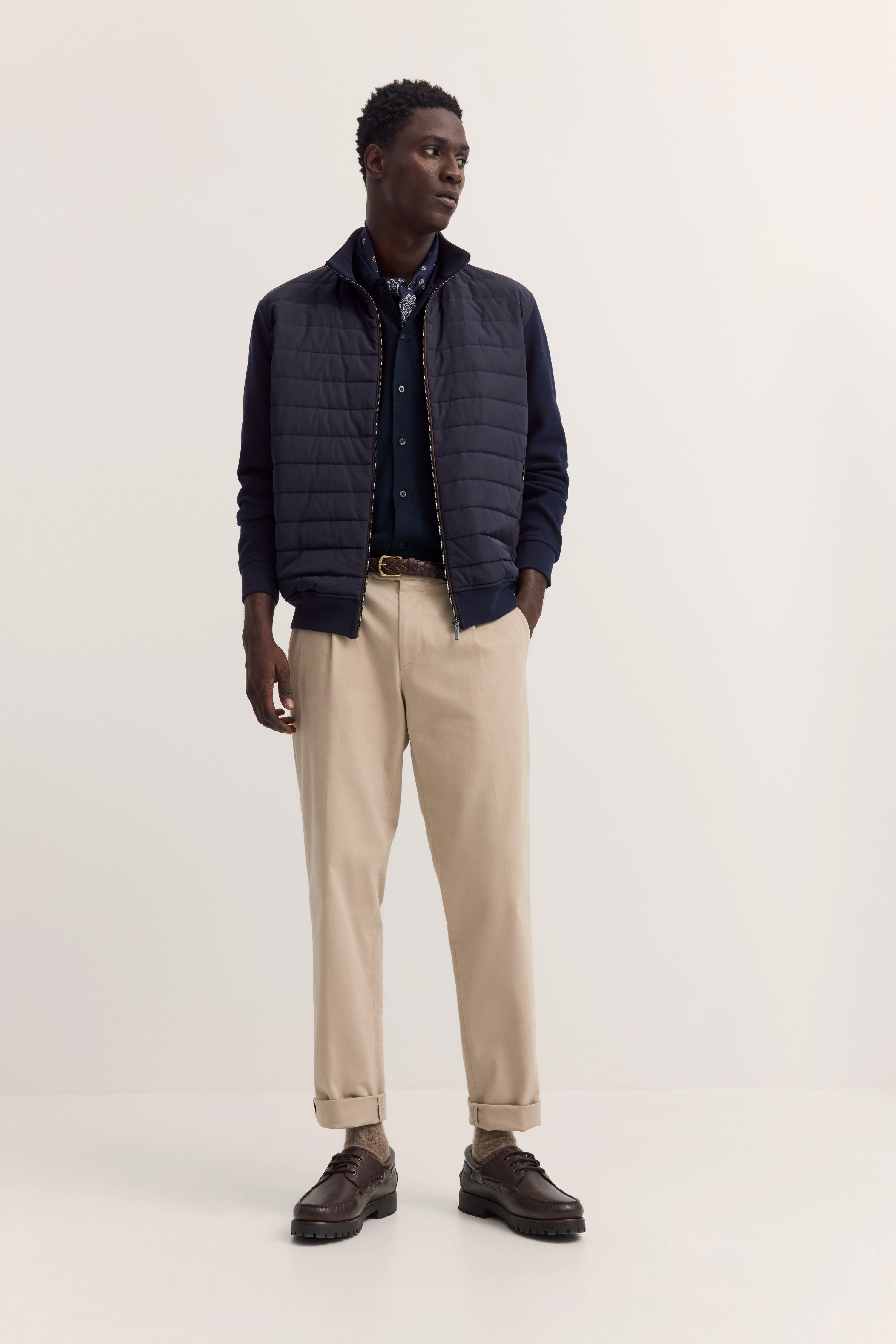 Model in navy Steppweste, Hemd, beige Hose. Lässig, selbstbewusstes Posing. bugatti Stil.