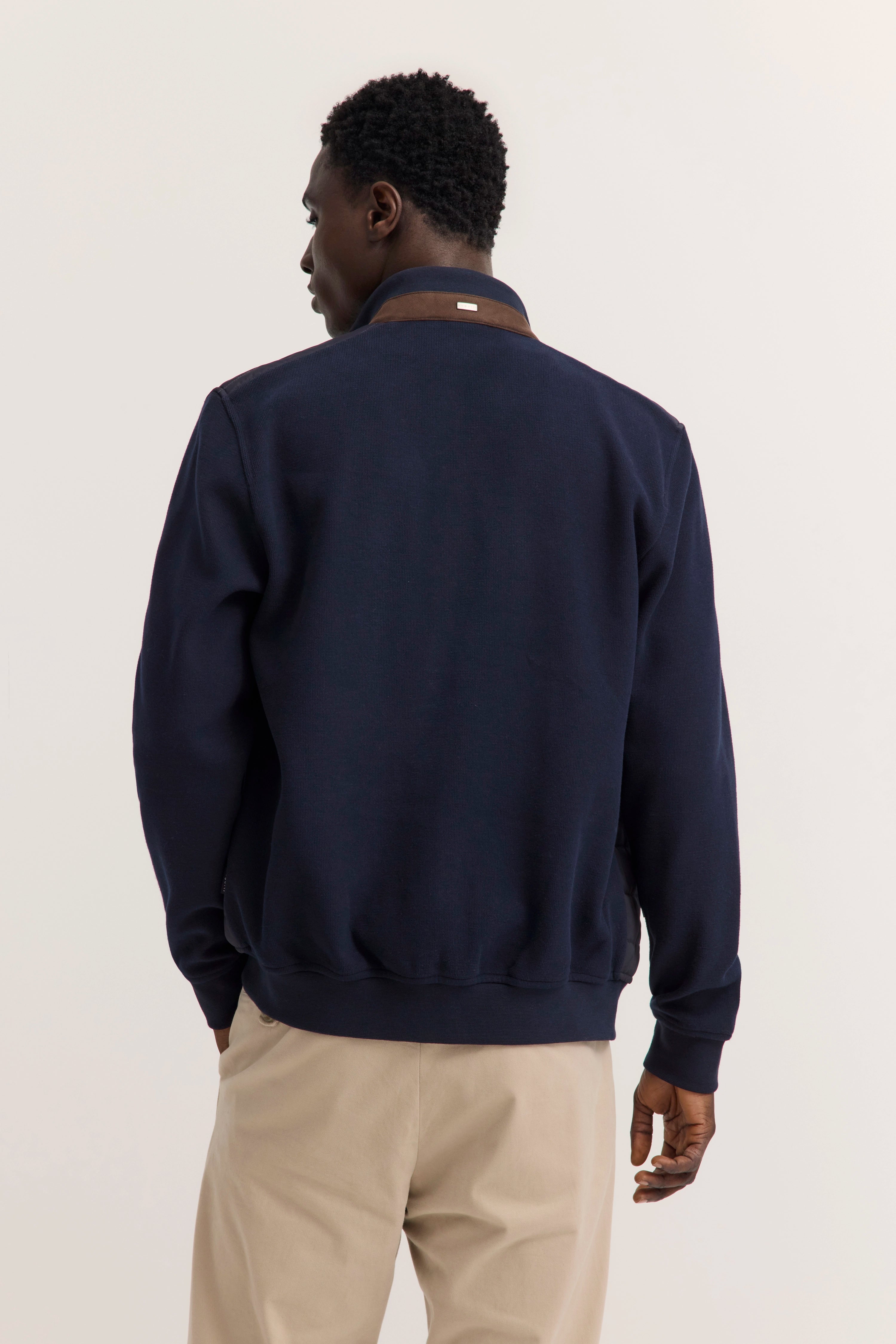 Model in navy bugatti Pullover und beigen Hosen, Rückansicht, entspanntes Posing.