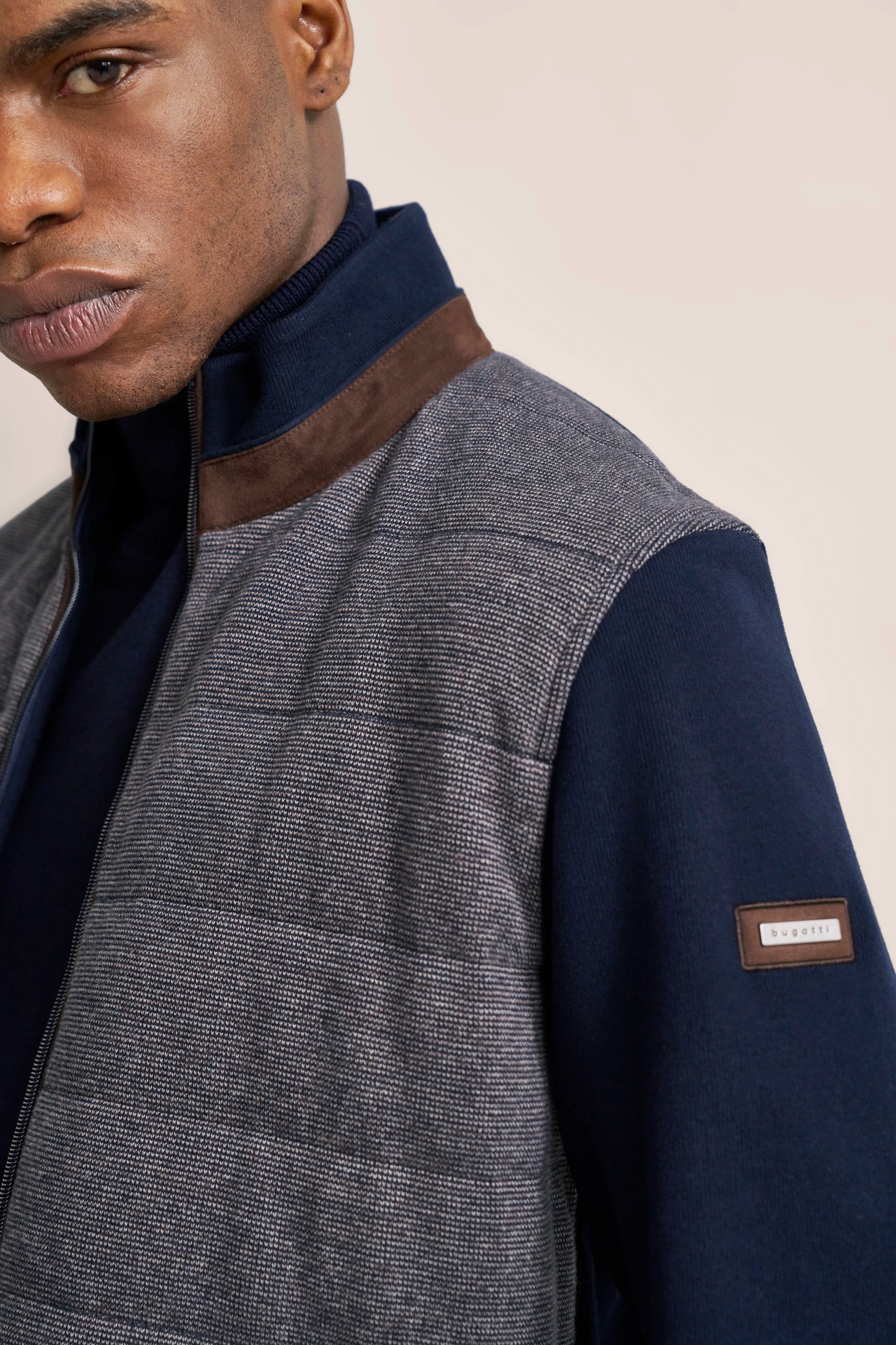 bugatti Modelbild, blau-graue Jacke mit braunem Kragen, sportlich-elegant, seitliches Portrait.