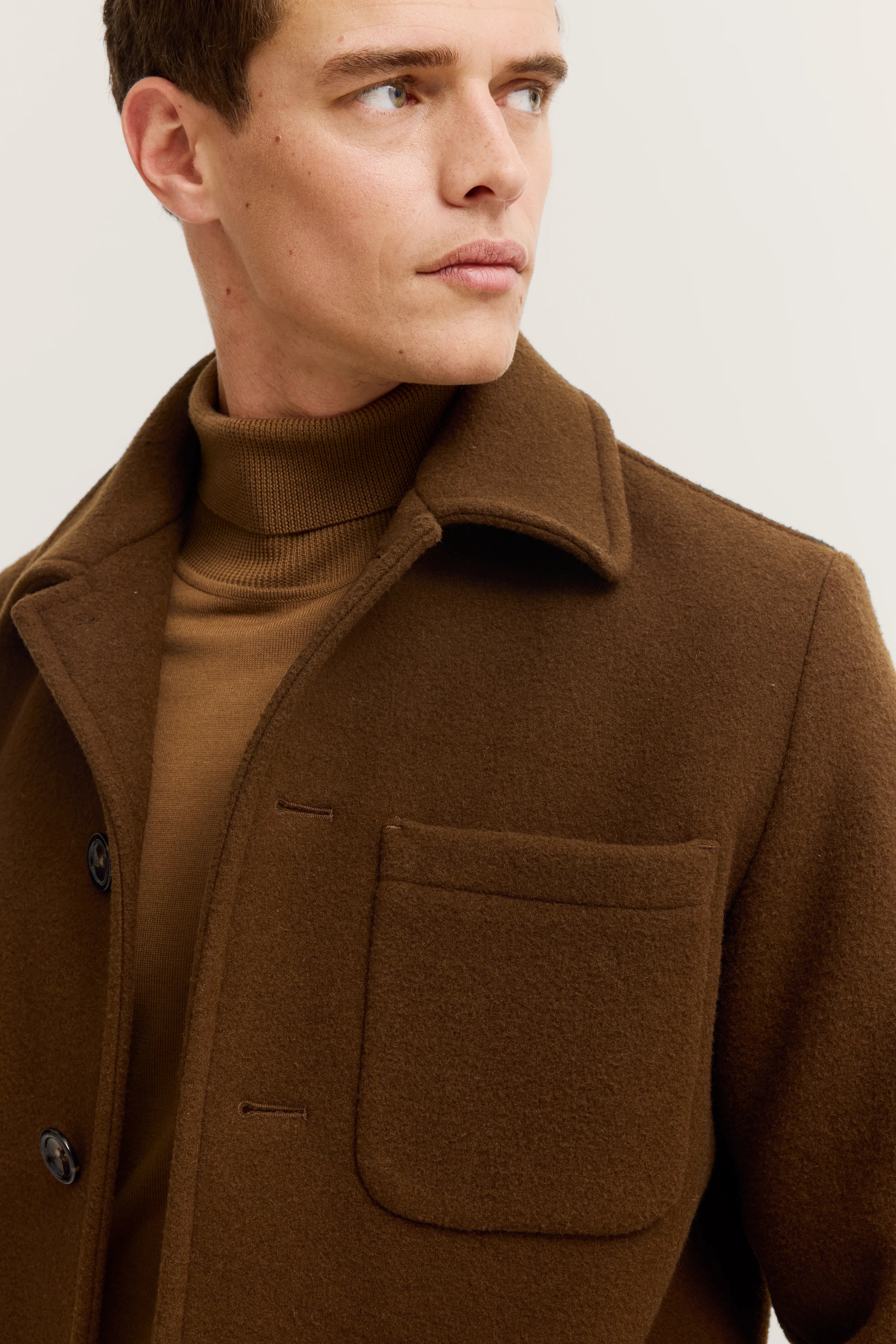 Brauner bugatti Mantel und Rollkragenpullover, Modelbild, Kopf zur Seite gewandt.