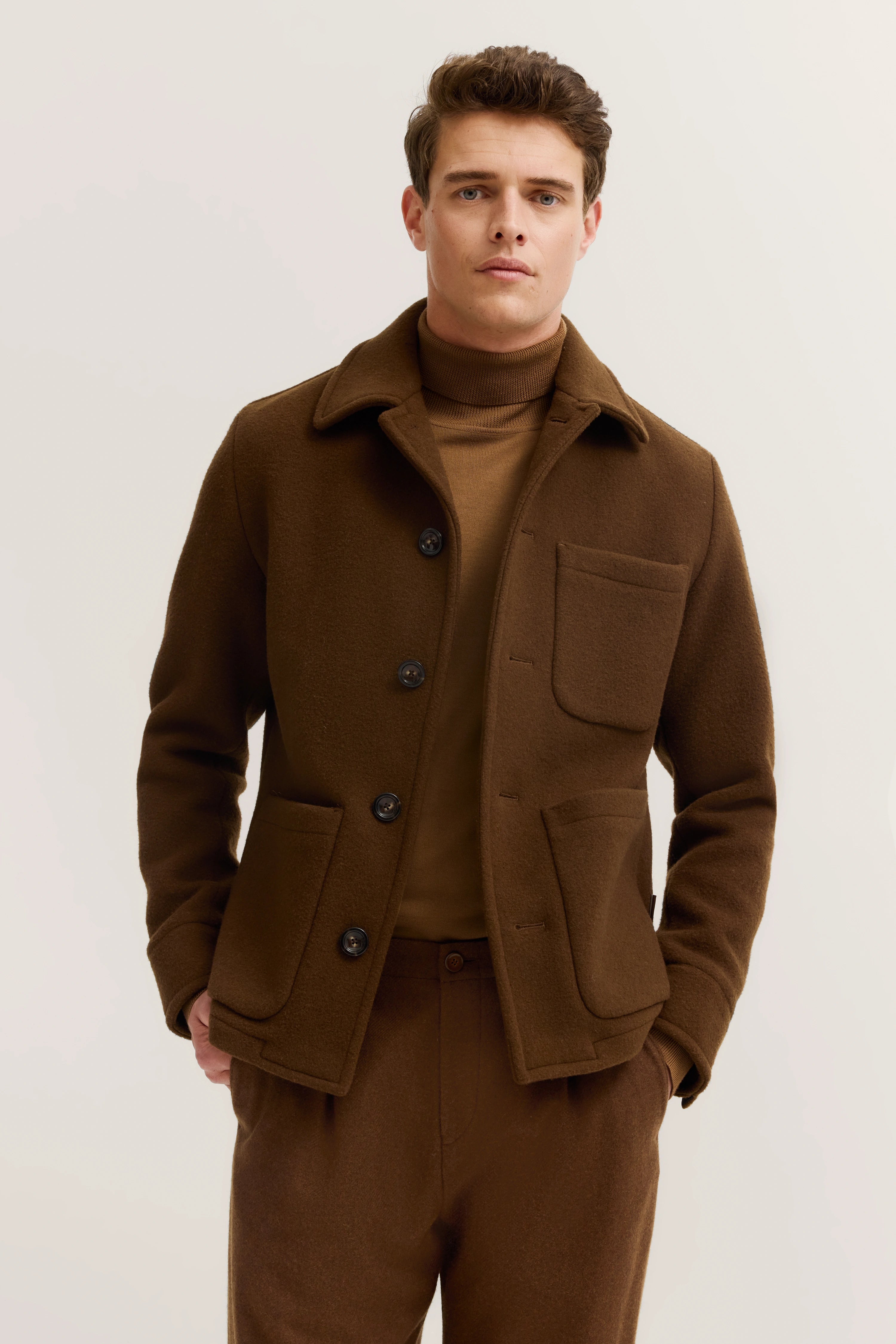 Braunes Outfit mit Jacke und Rollkragenpullover auf Modelbild, elegantes Posing.