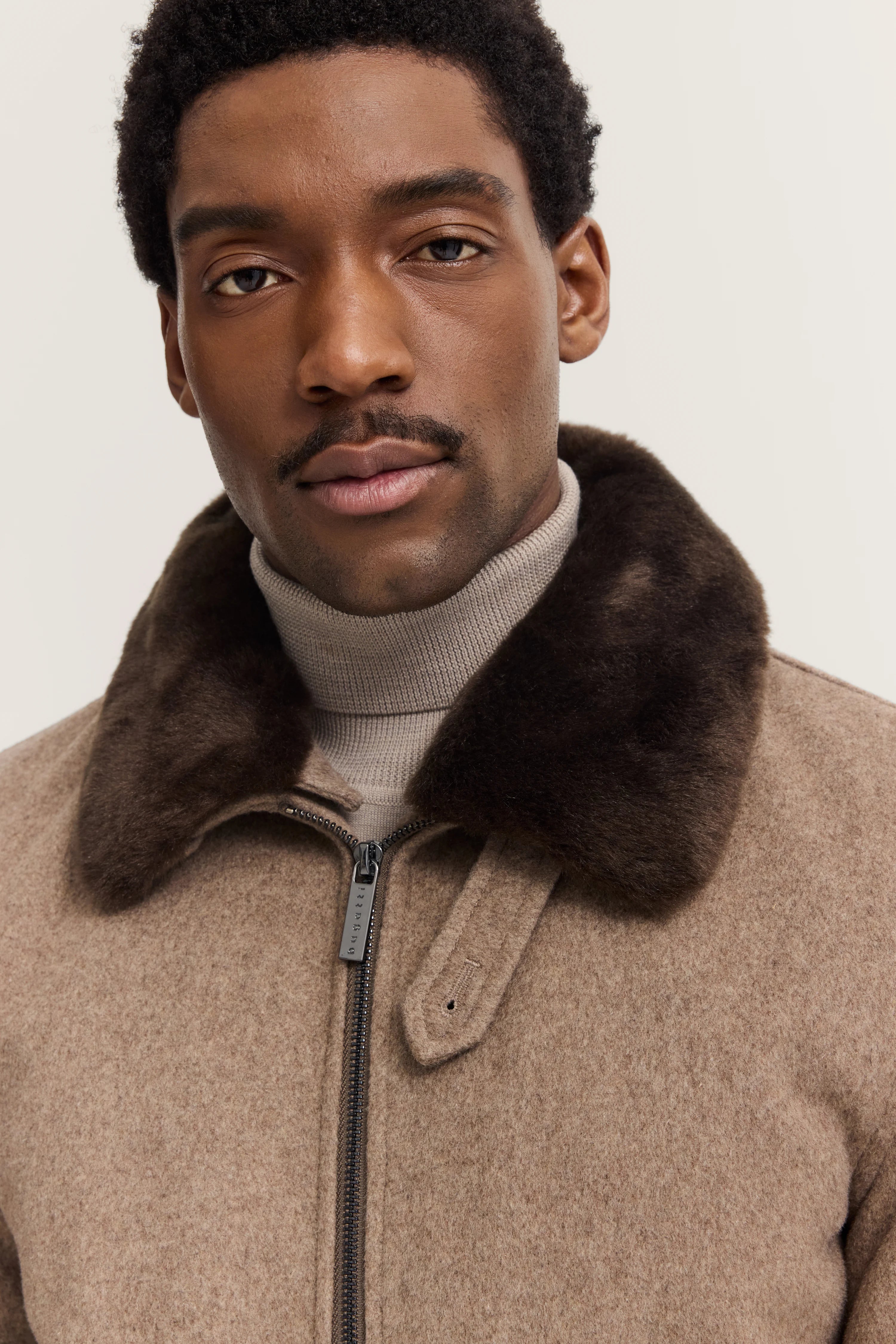 bugatti Jacke in Beige mit braunem Kragen, Rollkragenpullover in Taupe, Modelbild, entspannte Pose.