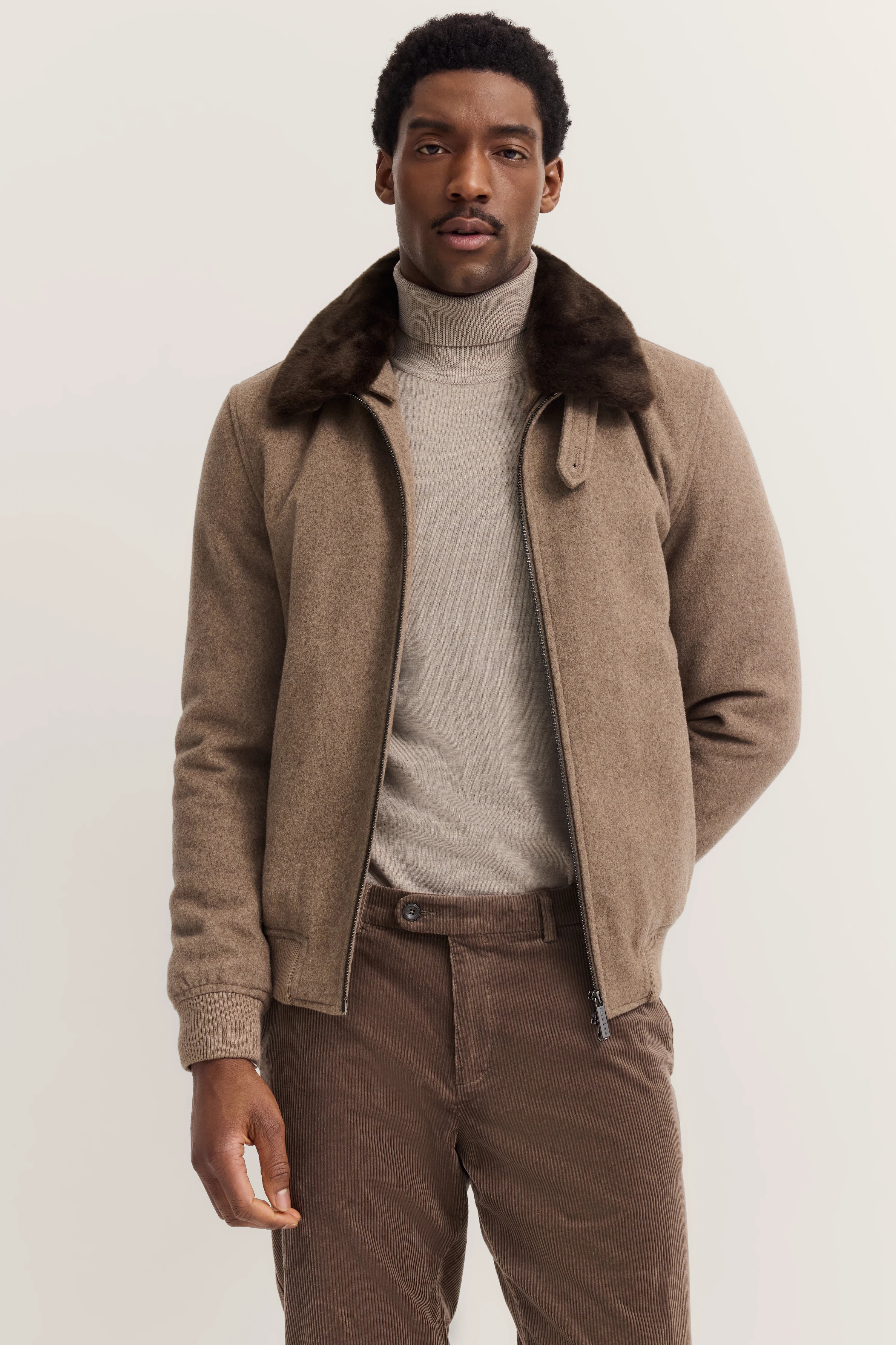 Brauner bugatti Blouson mit Fellkragen, Rollkragenpullover, Cordhose, Modelbild, entspannte Pose.