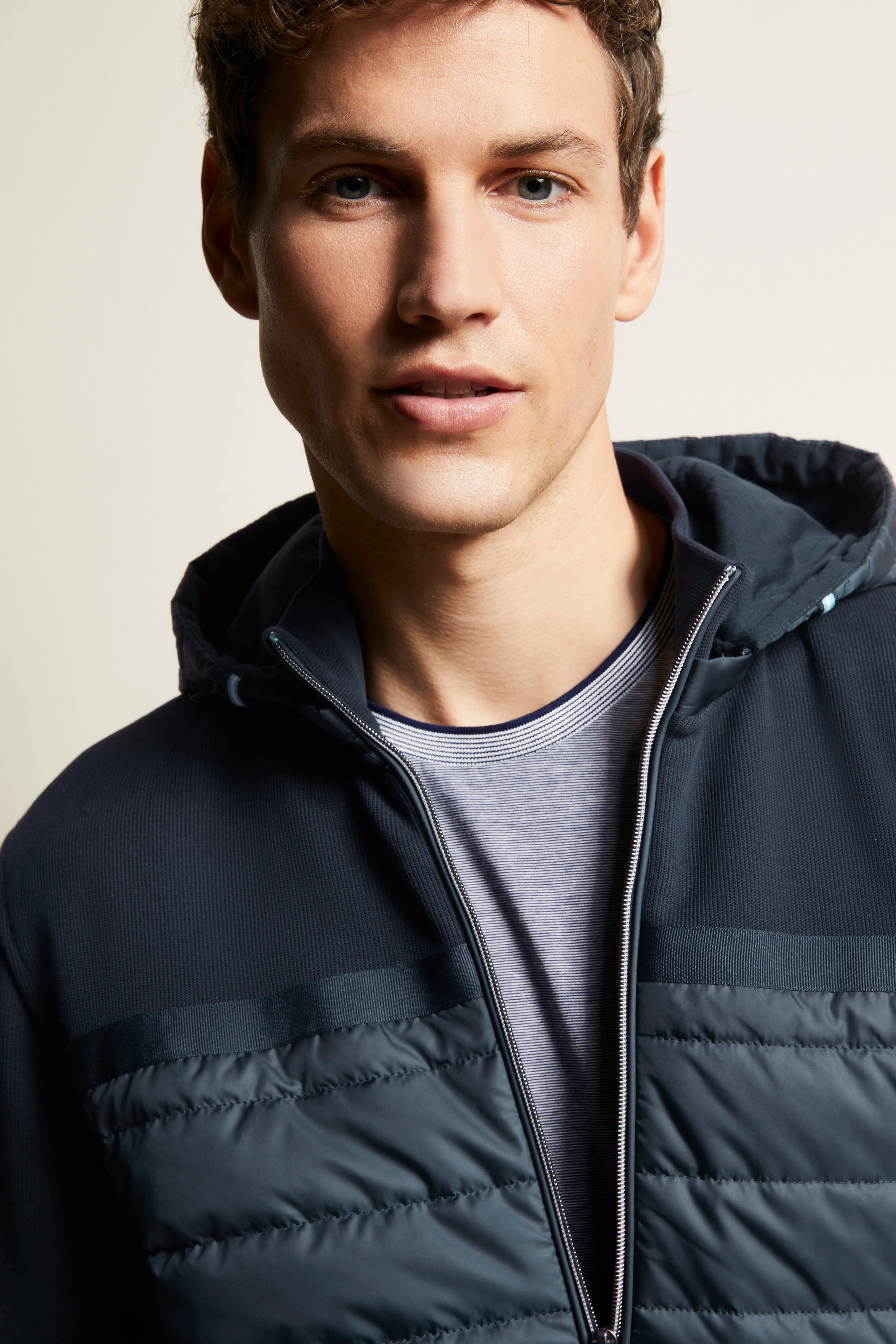 Bugatti Modelbild: Dunkelblaue Steppjacke, graues Shirt, legeres Posing.
