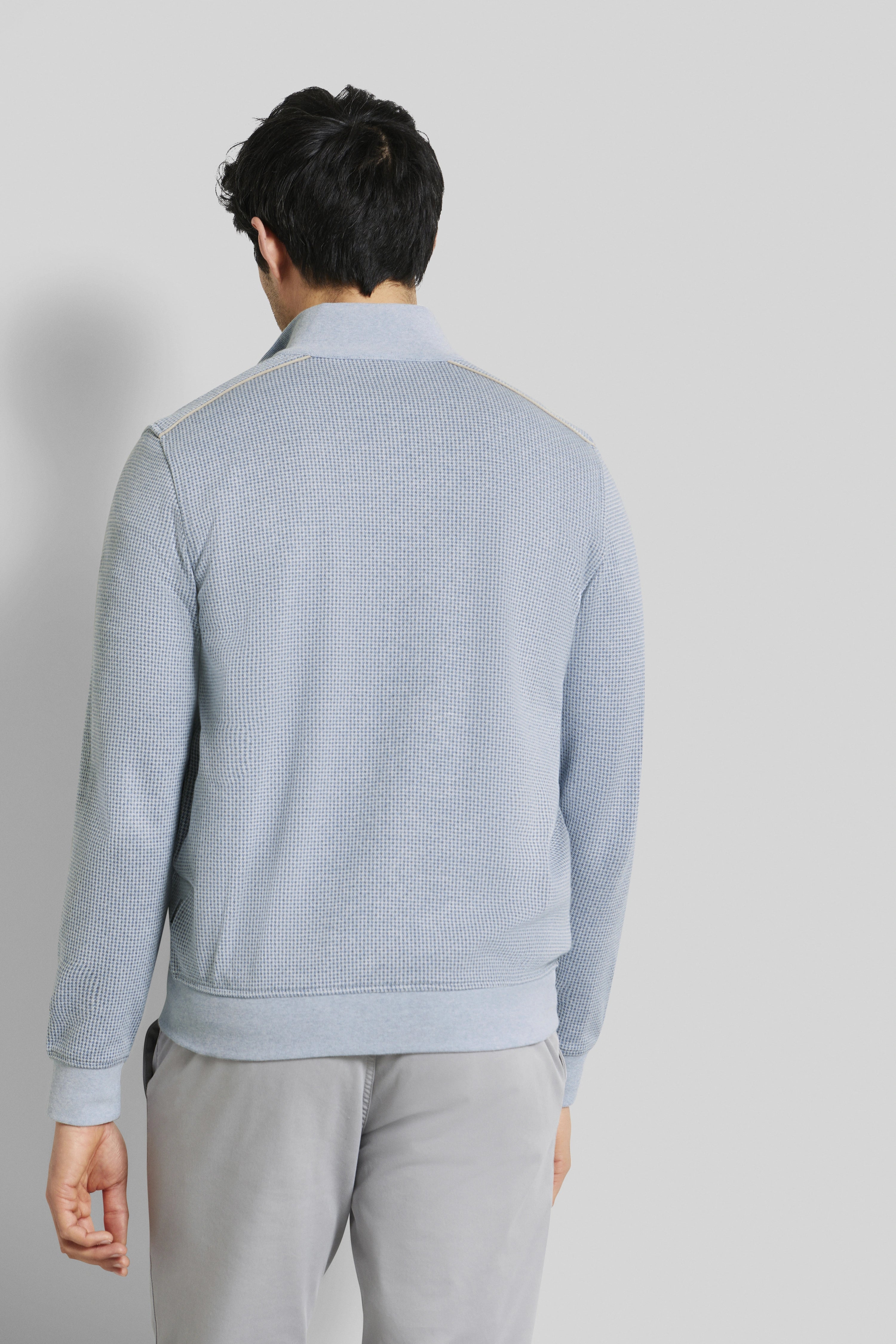 Herren-Model trägt hellblauen Strickpullover und graue Hose von bugatti, Rückenansicht.