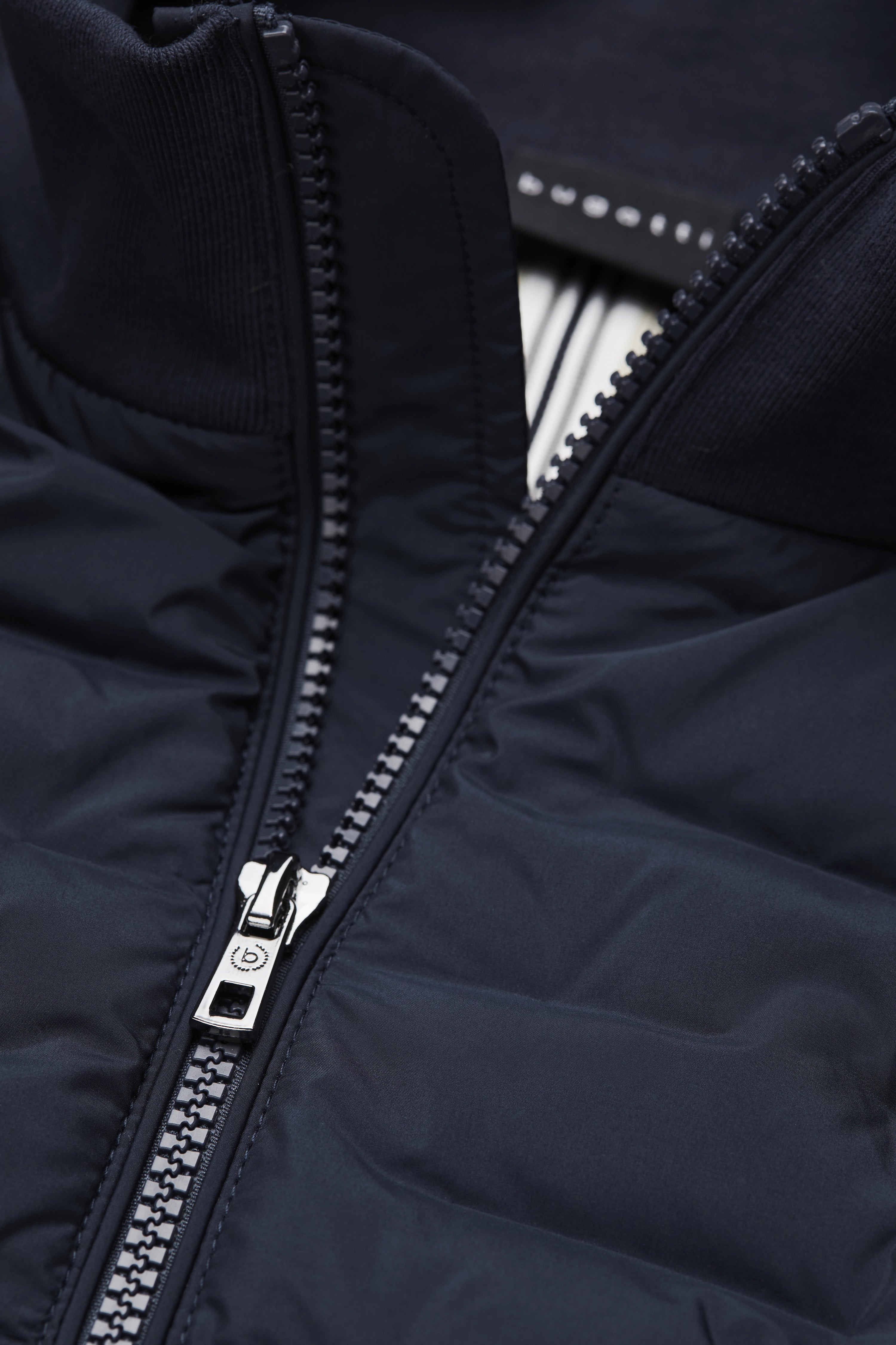 Dunkelblaue Steppjacke von bugatti mit Reißverschluss, Detailansicht des Kragens, hochwertiges Material.
