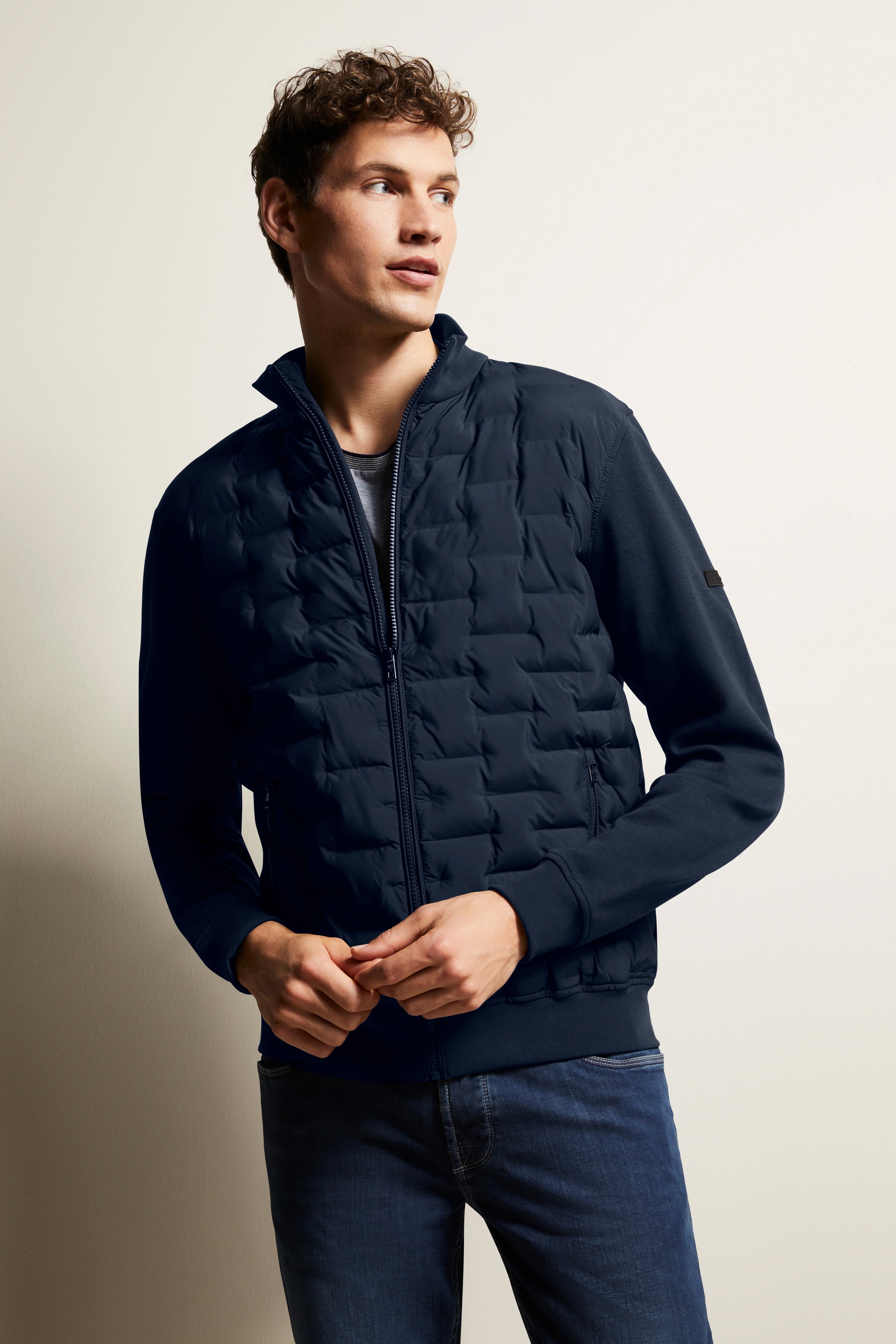 Navy Steppjacke und Jeans, Model posiert lässig, bugatti Stil und Qualität.