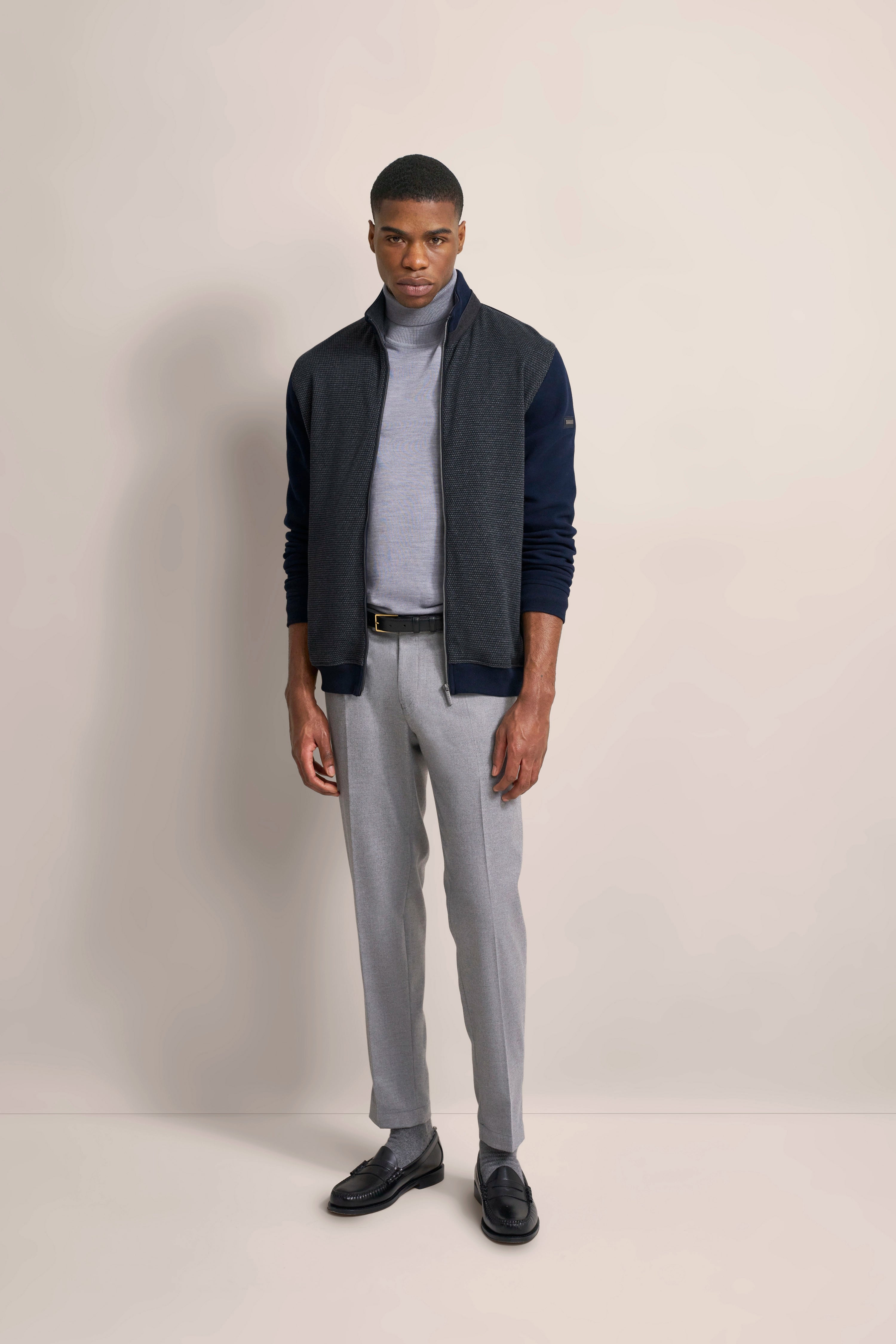 Model in grauem Rollkragen, dunkelblauer Jacke, grauer Hose