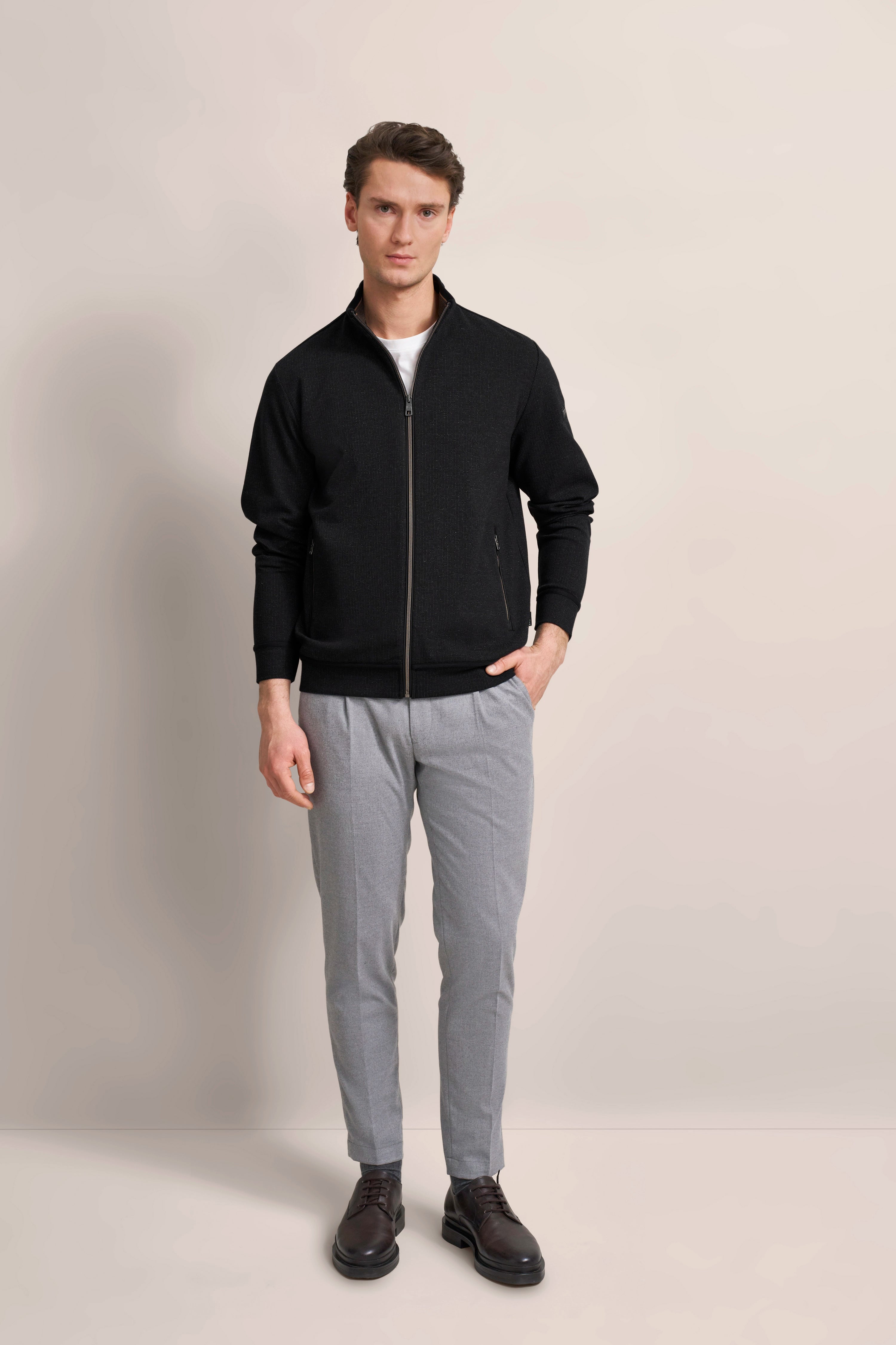 Model in schwarzer bugatti Jacke, grauer Hose, braunen Schuhen