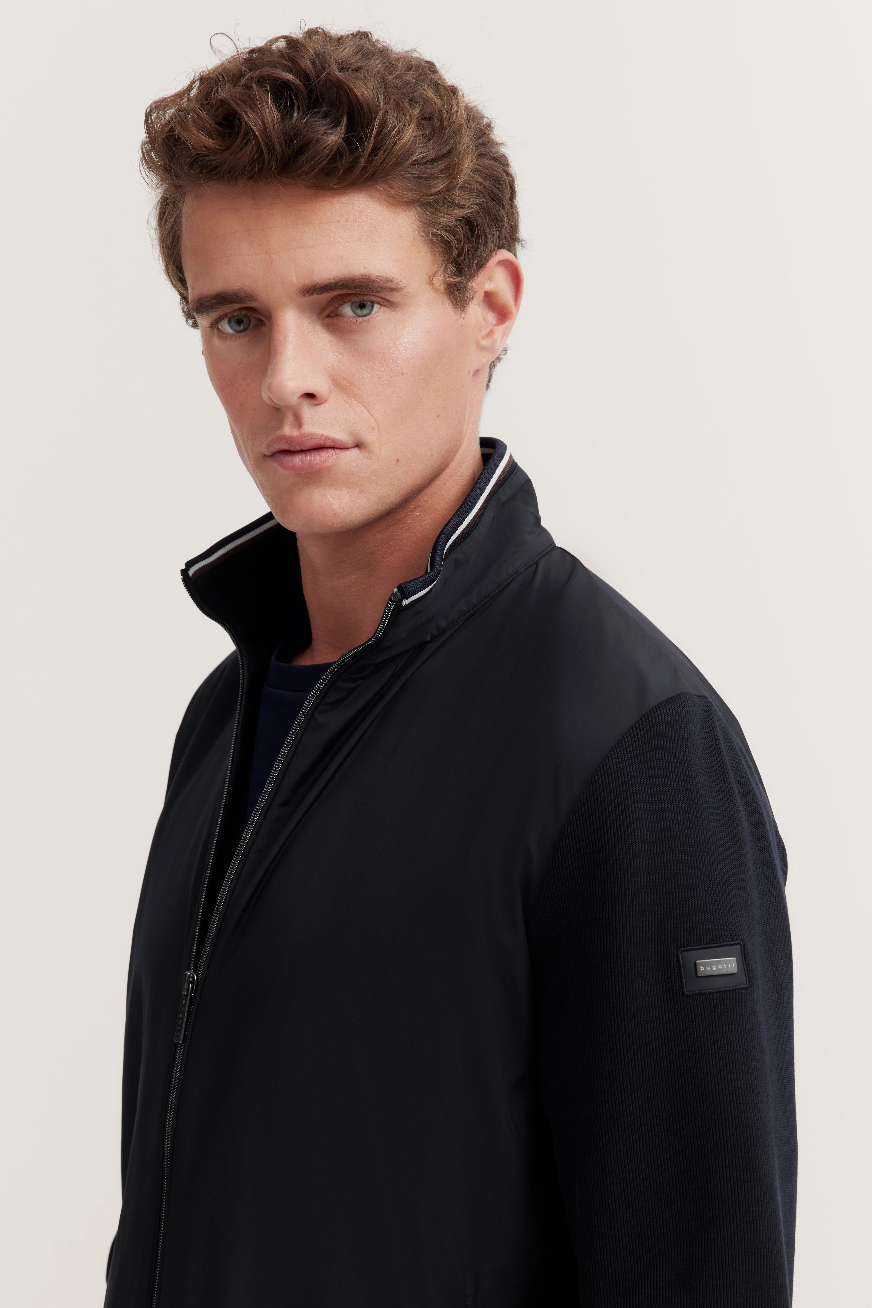 bugatti Model in schwarzer Jacke, legerer Look, zeitloser Stil, entspannter Ausdruck.