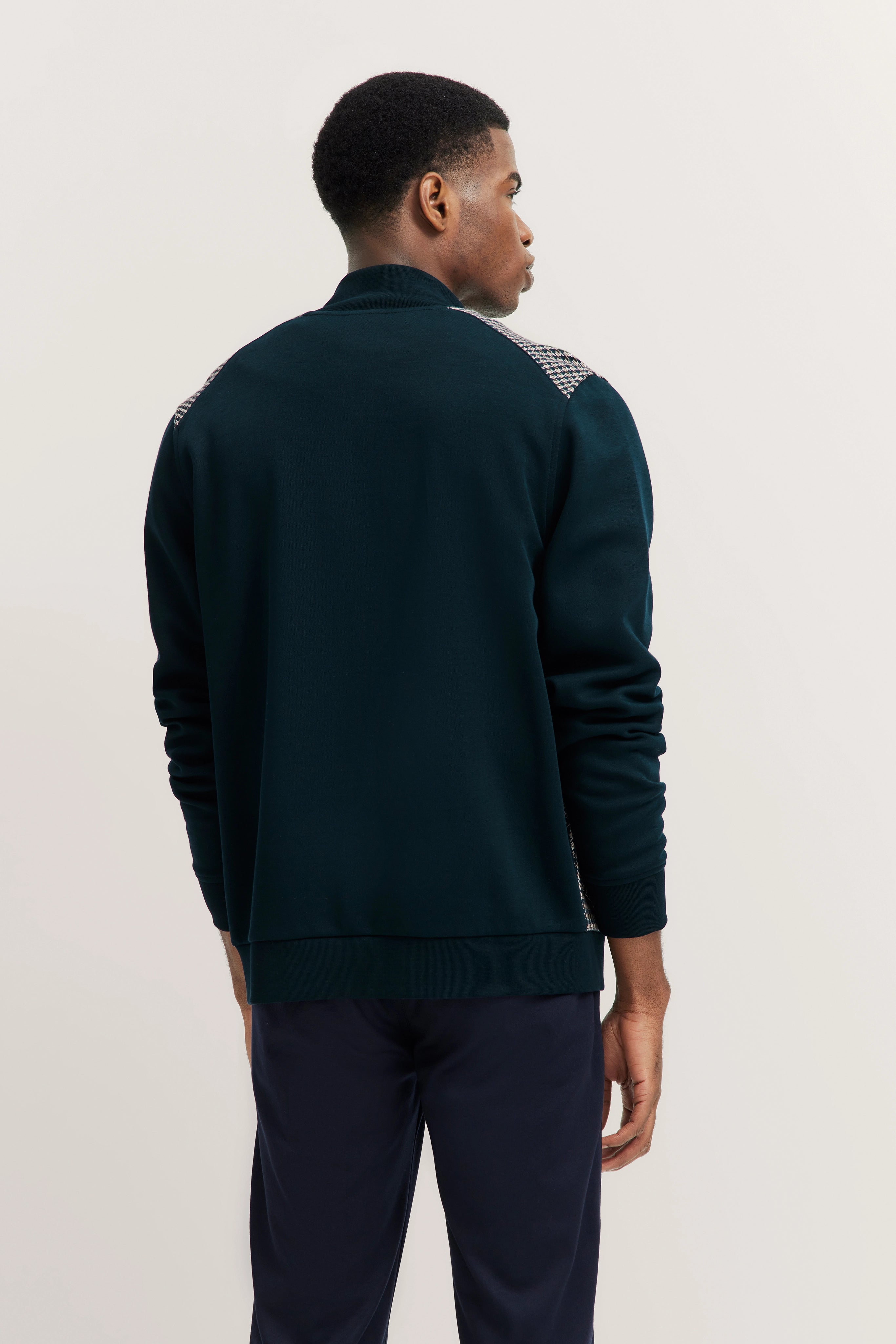 Model in dunkelblauer bugatti Jacke mit gemusterten Schultern, seitliches Posing.
