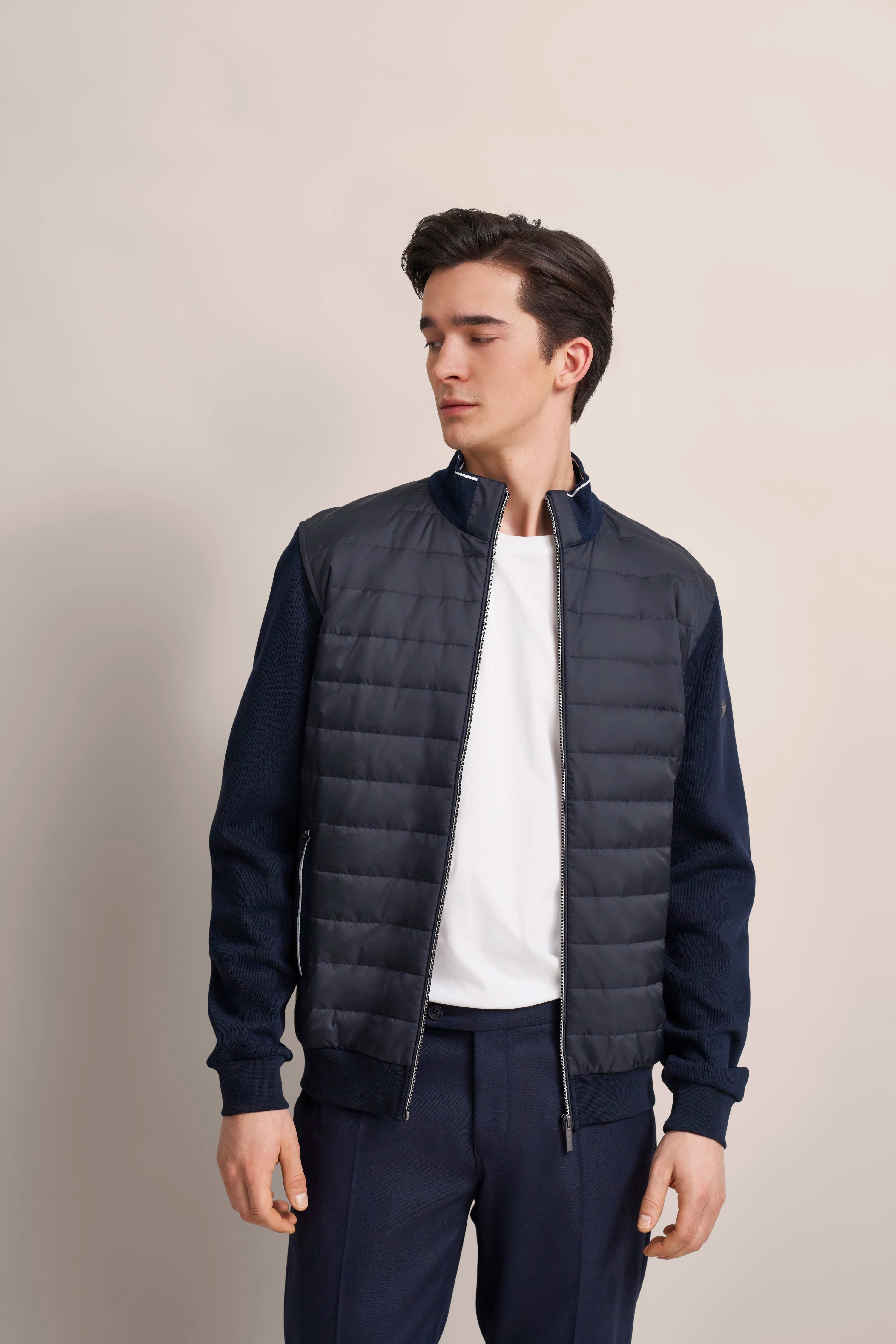 Dunkelblaue bugatti Jacke, weißes Shirt, Model stehend, entspanntes Posing.