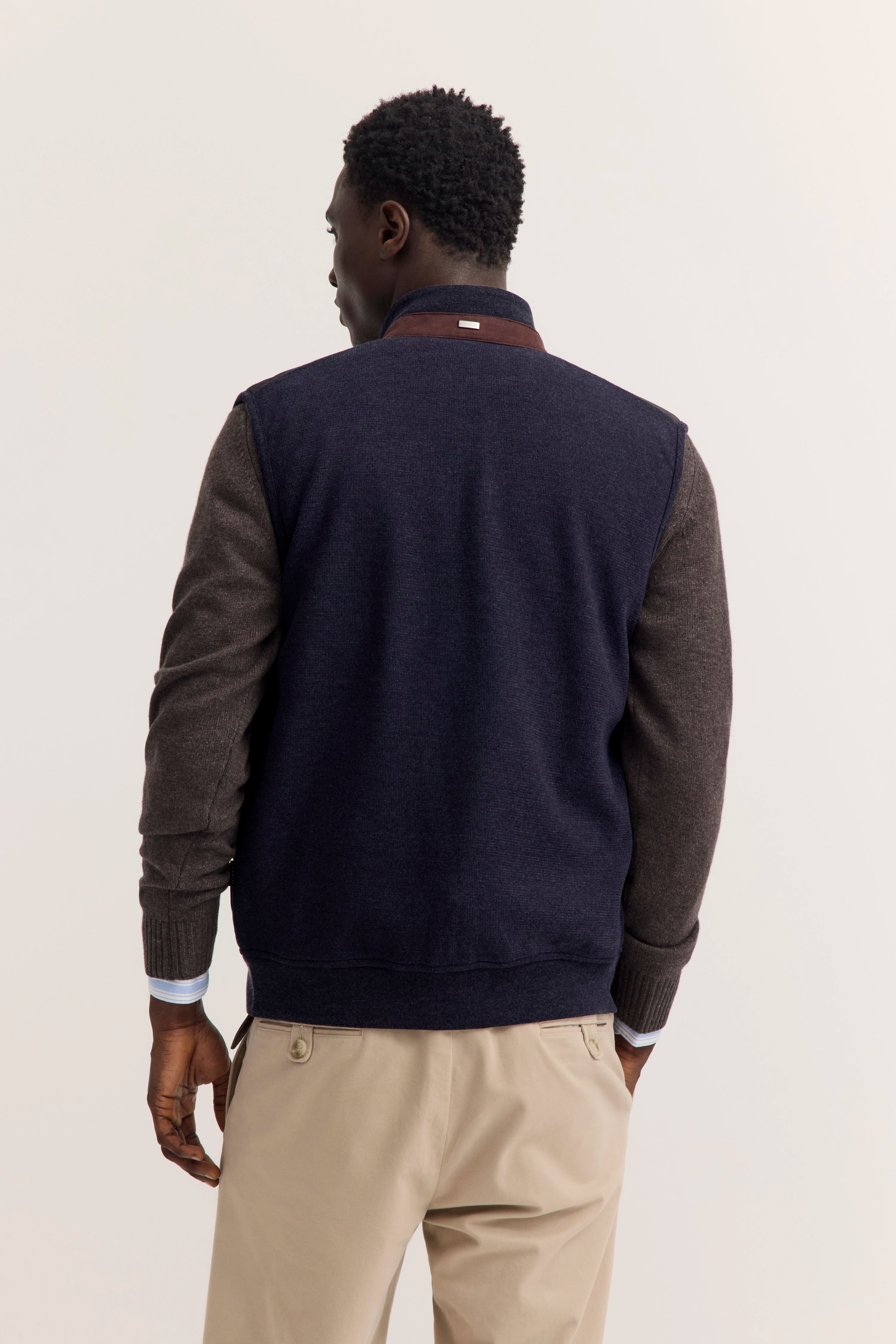 bugatti Herrenmodel von hinten in marineblauer Jacke, grauen Ärmeln, beigem Chino und legerem Posing.