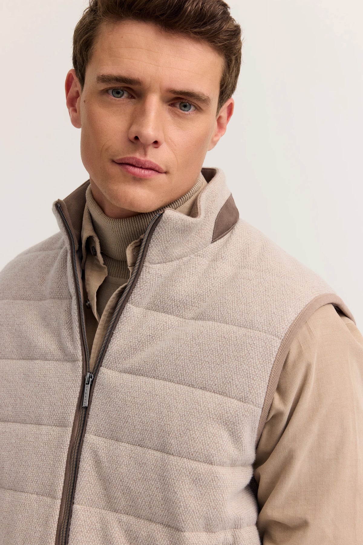 Bugatti Model in beiger Steppweste und Rollkragenpullover, legerer Look.